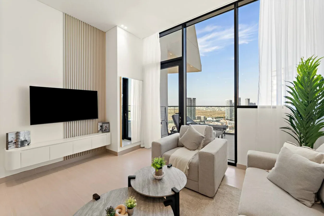 Una sala luminosa con asientos, un televisor y ventanas de piso a techo.