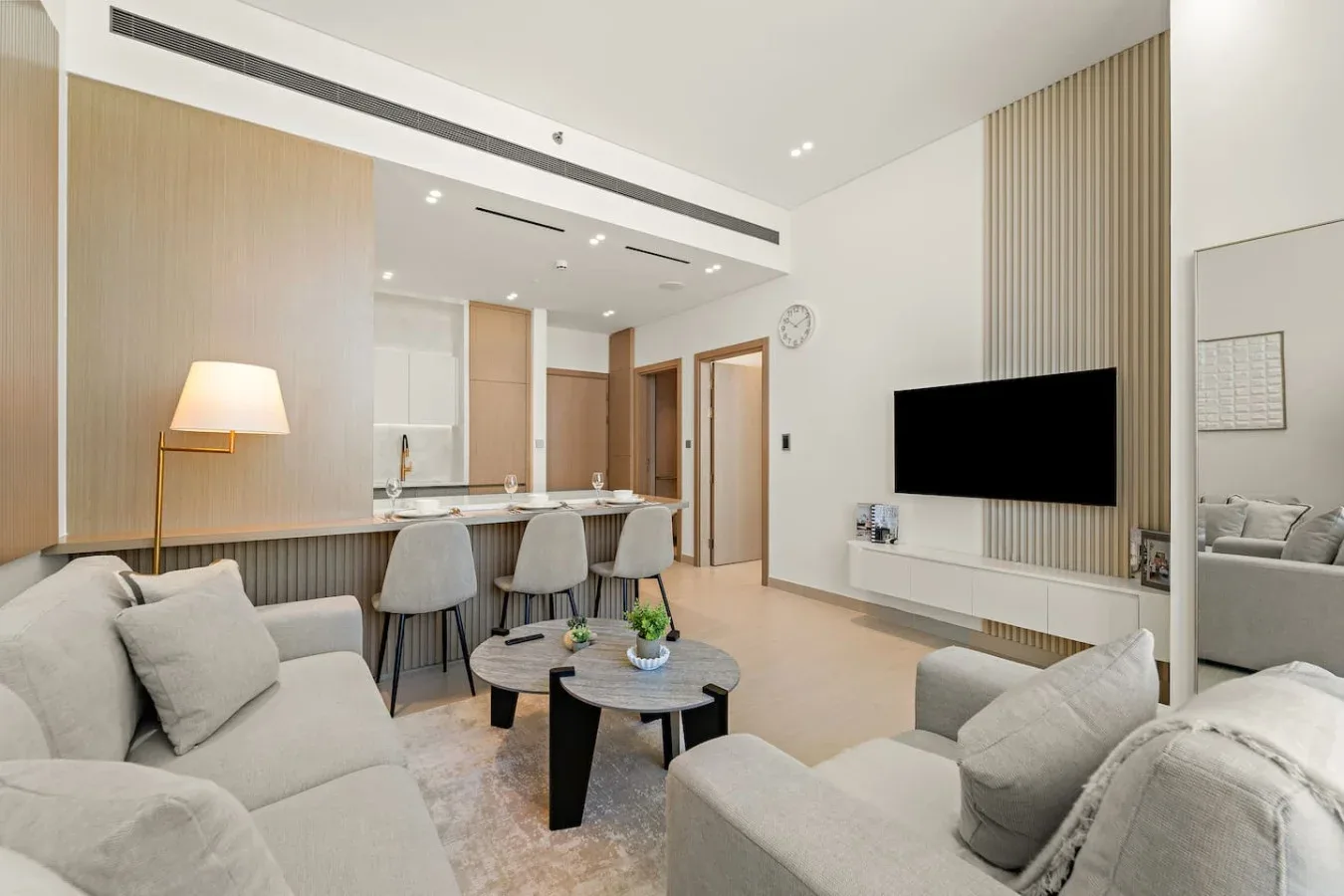 Una sala luminosa con asientos, un televisor y una barra de cocina.