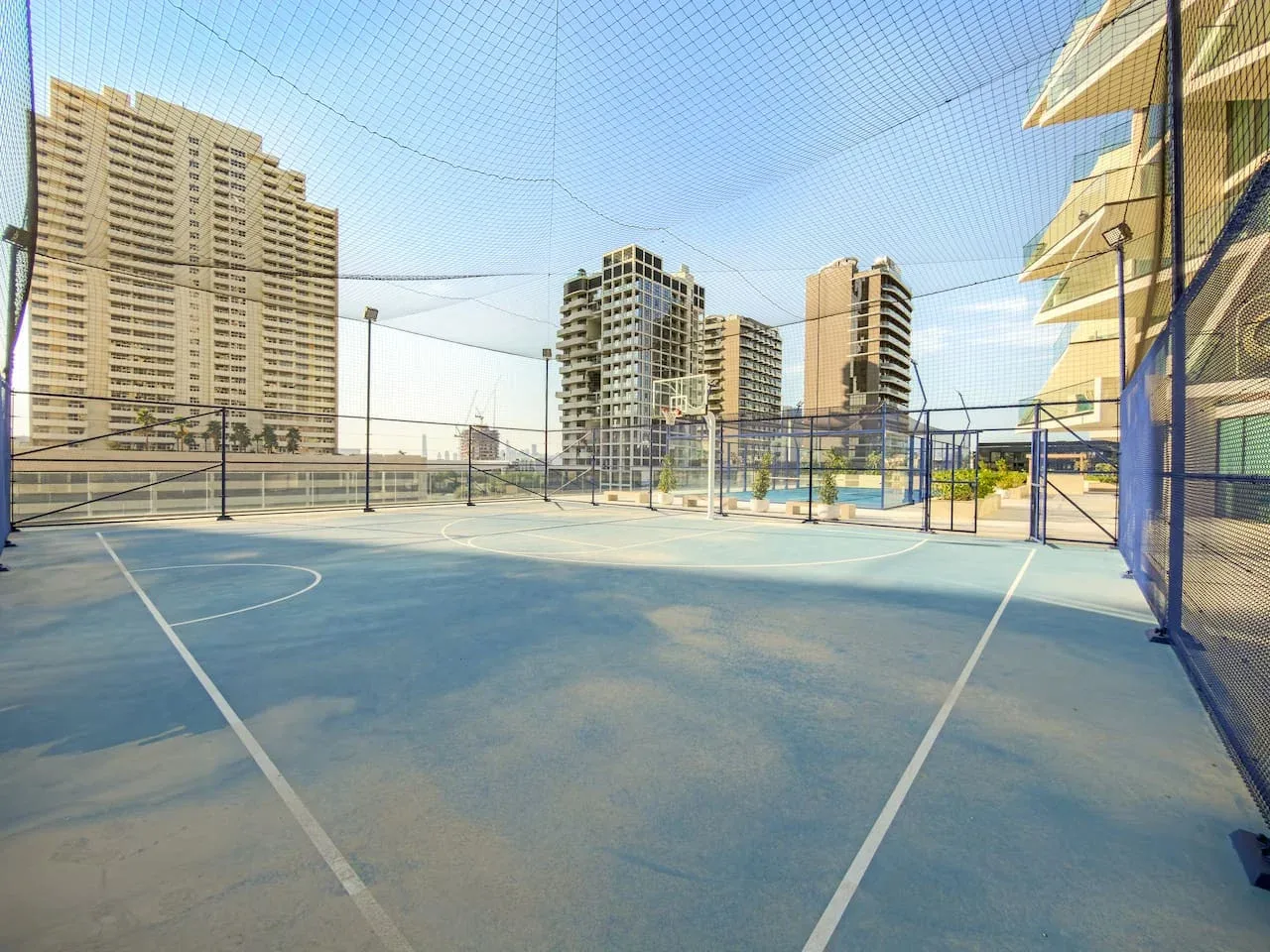 Una cancha deportiva al aire libre con edificios altos y una red de protección.