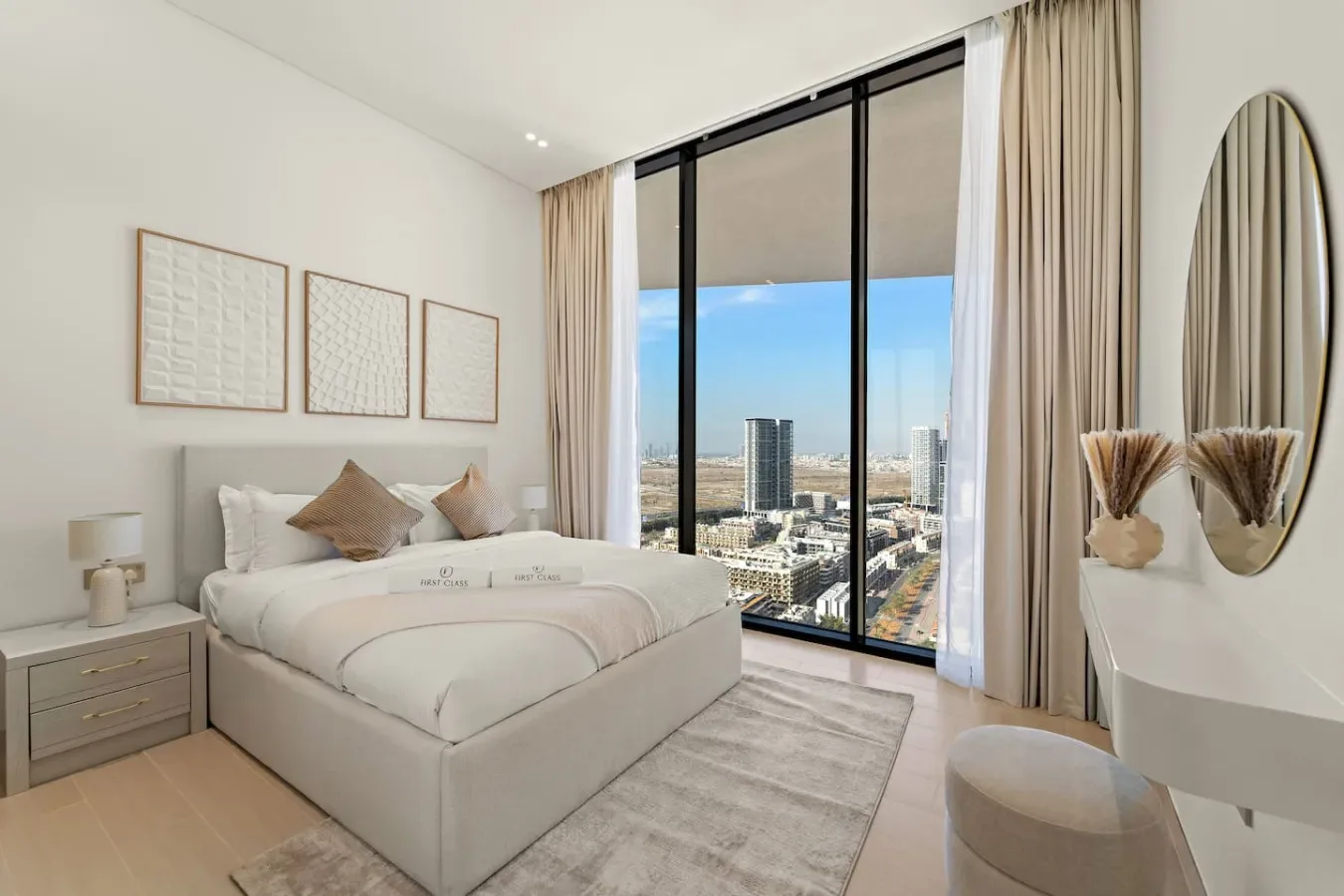 Un dormitorio luminoso con una cama tendida junto a un gran ventanal con vistas a la ciudad.