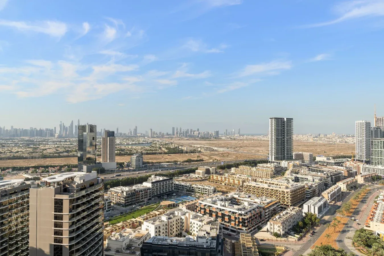 Un amplio paisaje urbano muestra edificios altos y bloques residenciales bajo un cielo azul.