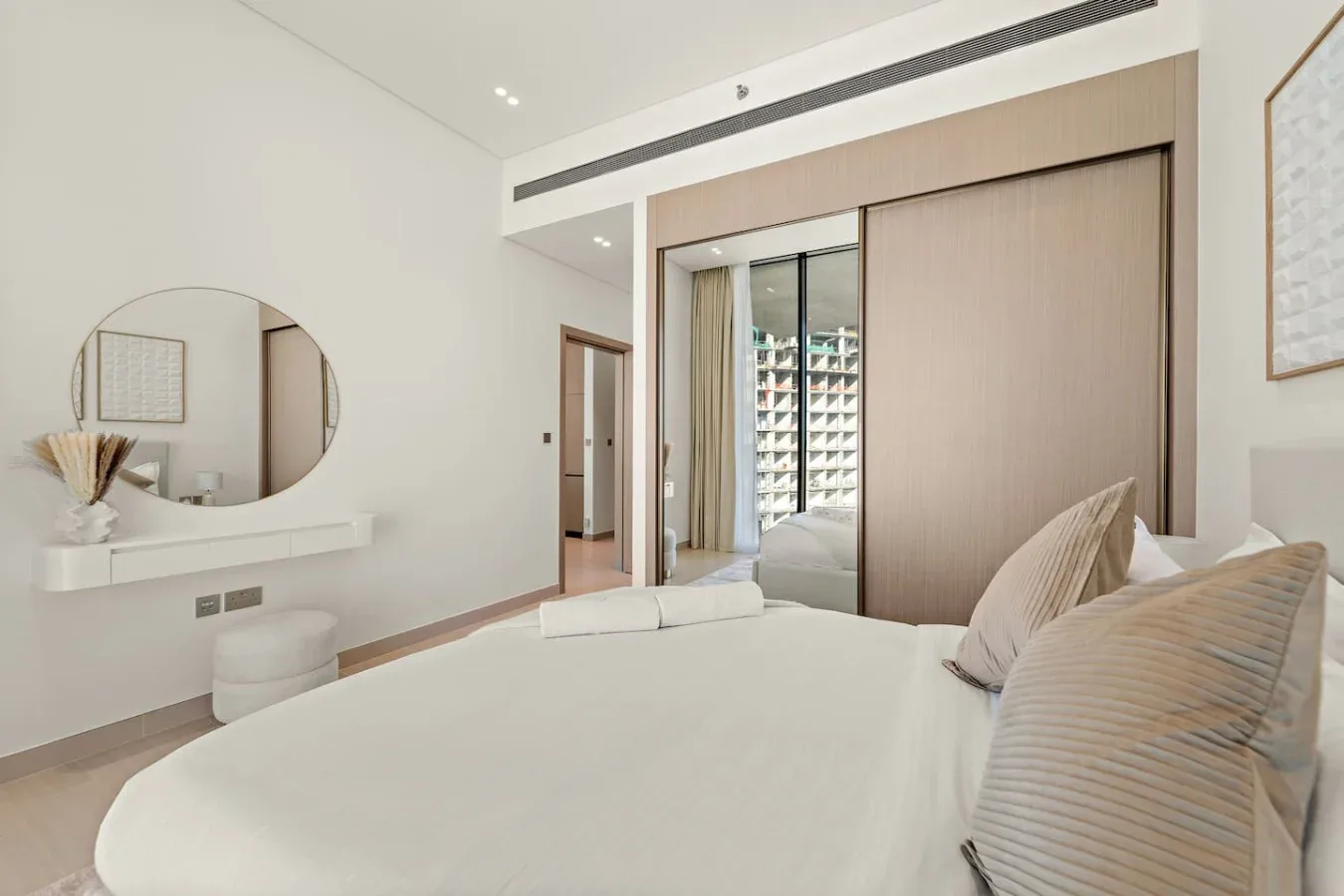 Un dormitorio luminoso con una cama grande y puertas correderas de armario con espejo.