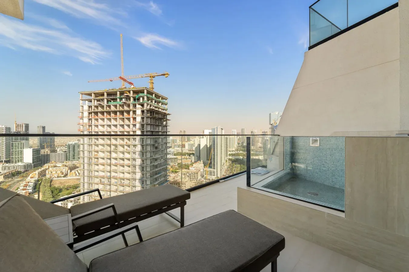 Una terraza en la azotea con asientos y una barandilla de vidrio ofrece vistas de la ciudad.