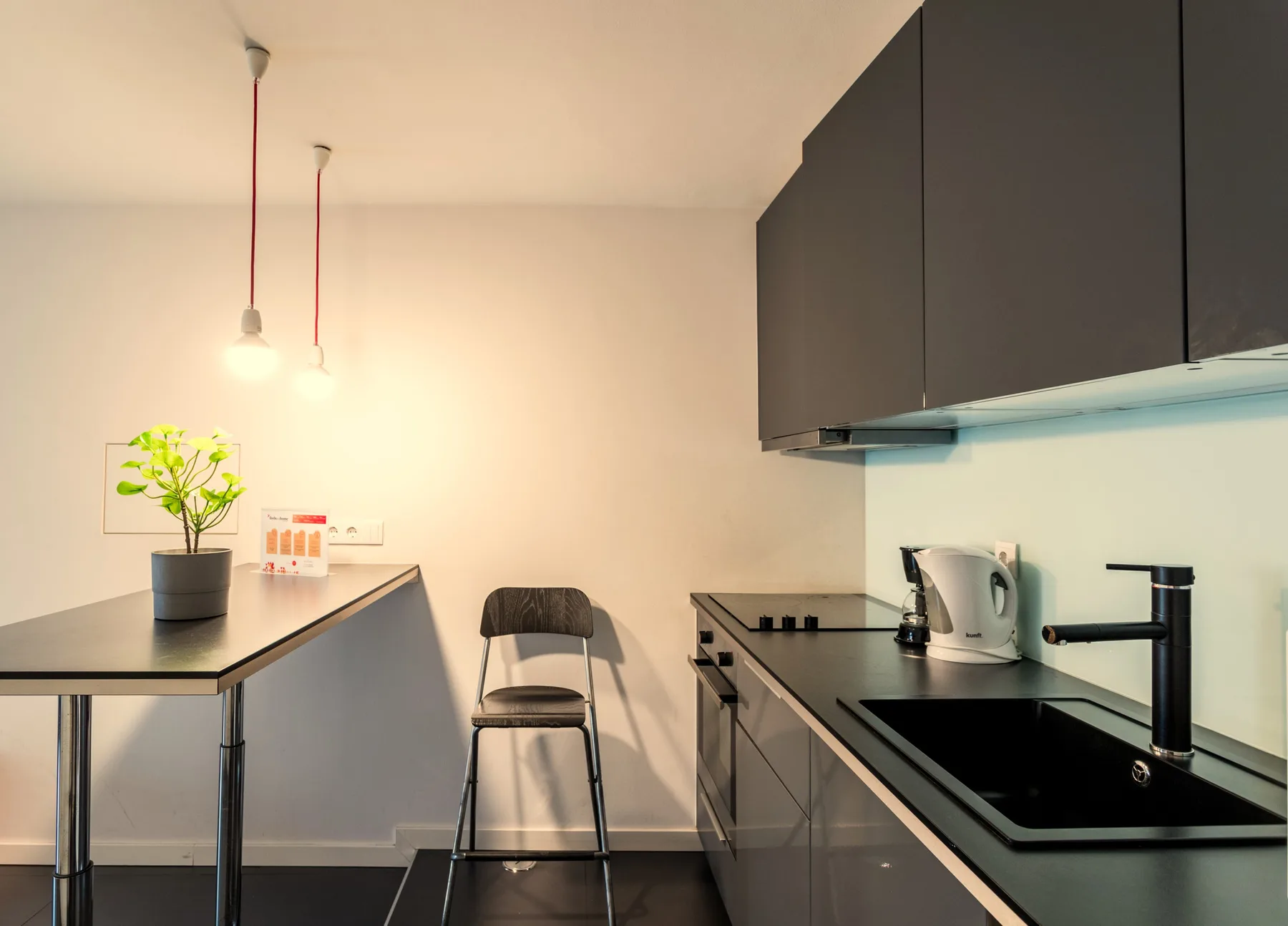 Una cocina compacta con una encimera, asientos y una planta en maceta.