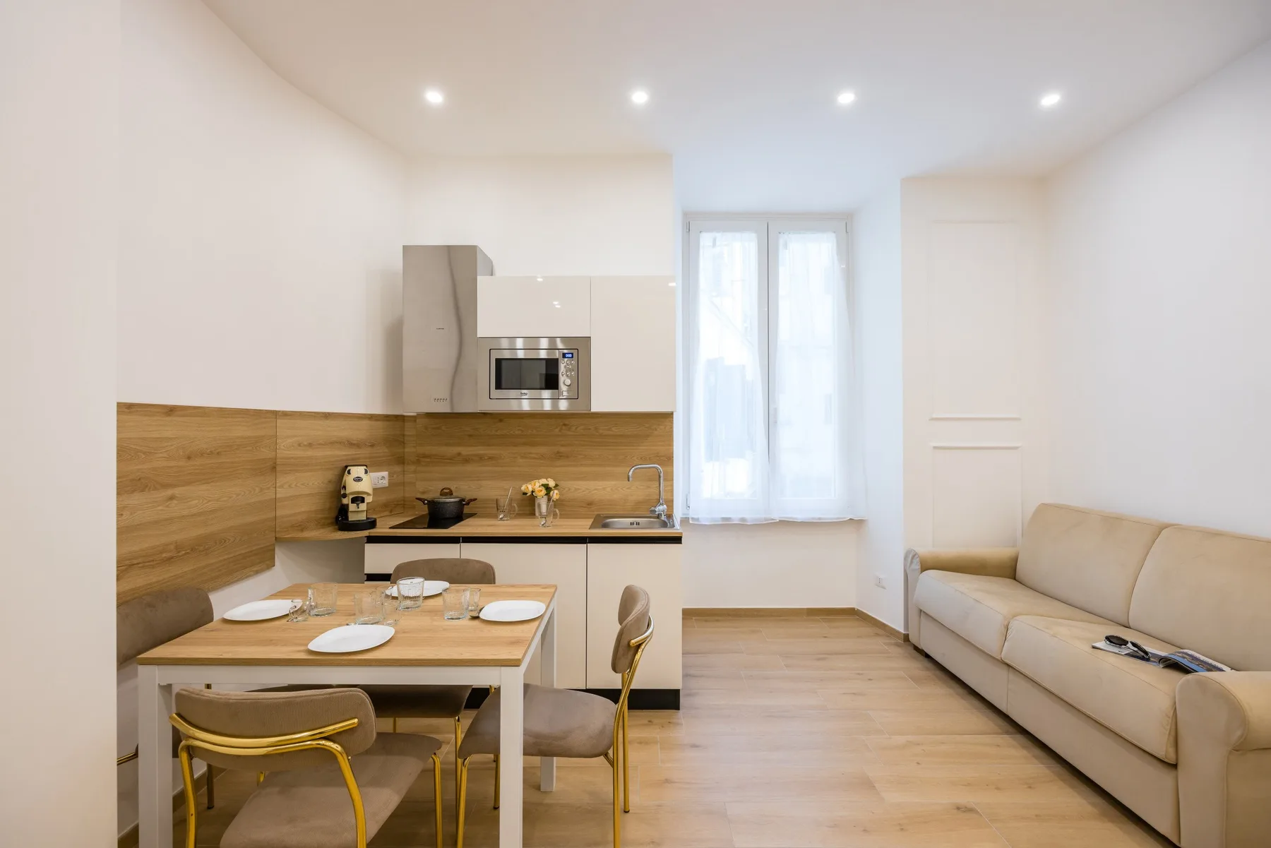 Una habitación luminosa y abierta con cocina compacta, mesa de comedor y asientos.