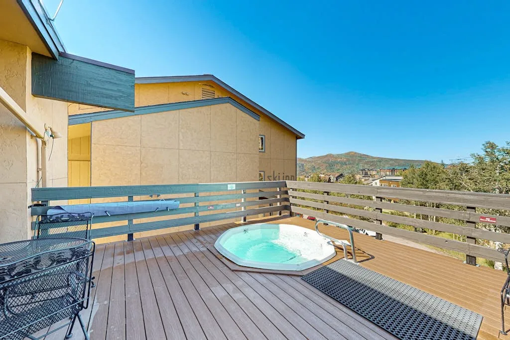 An outdoor deck with a built-in hot tub and views of the surrounding hills.