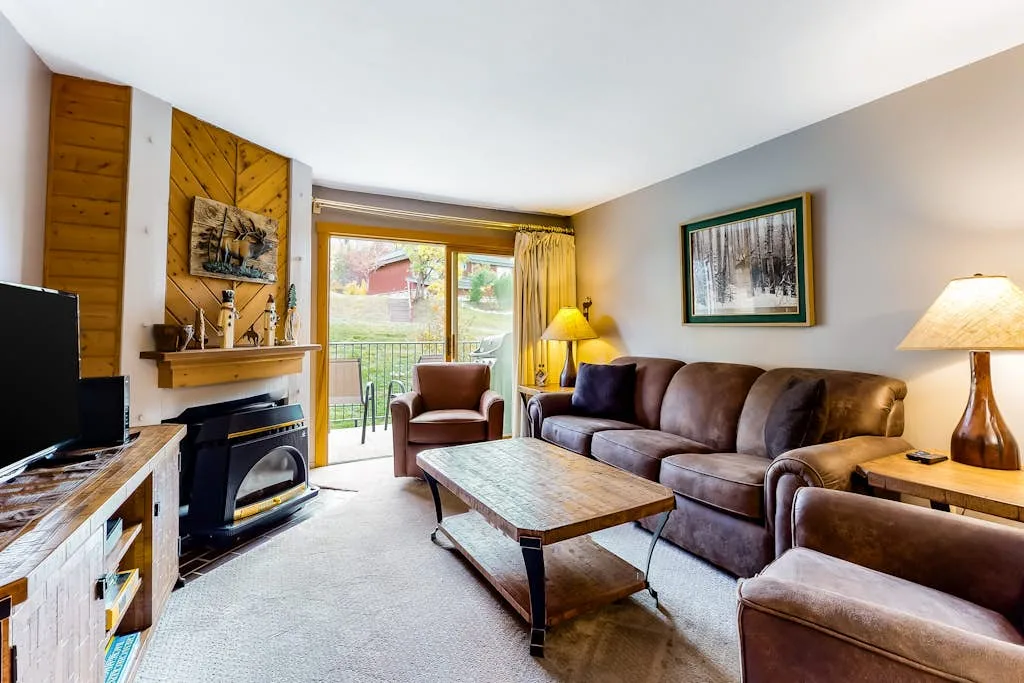 A living room with a brown sofa, a coffee table, and a fireplace.