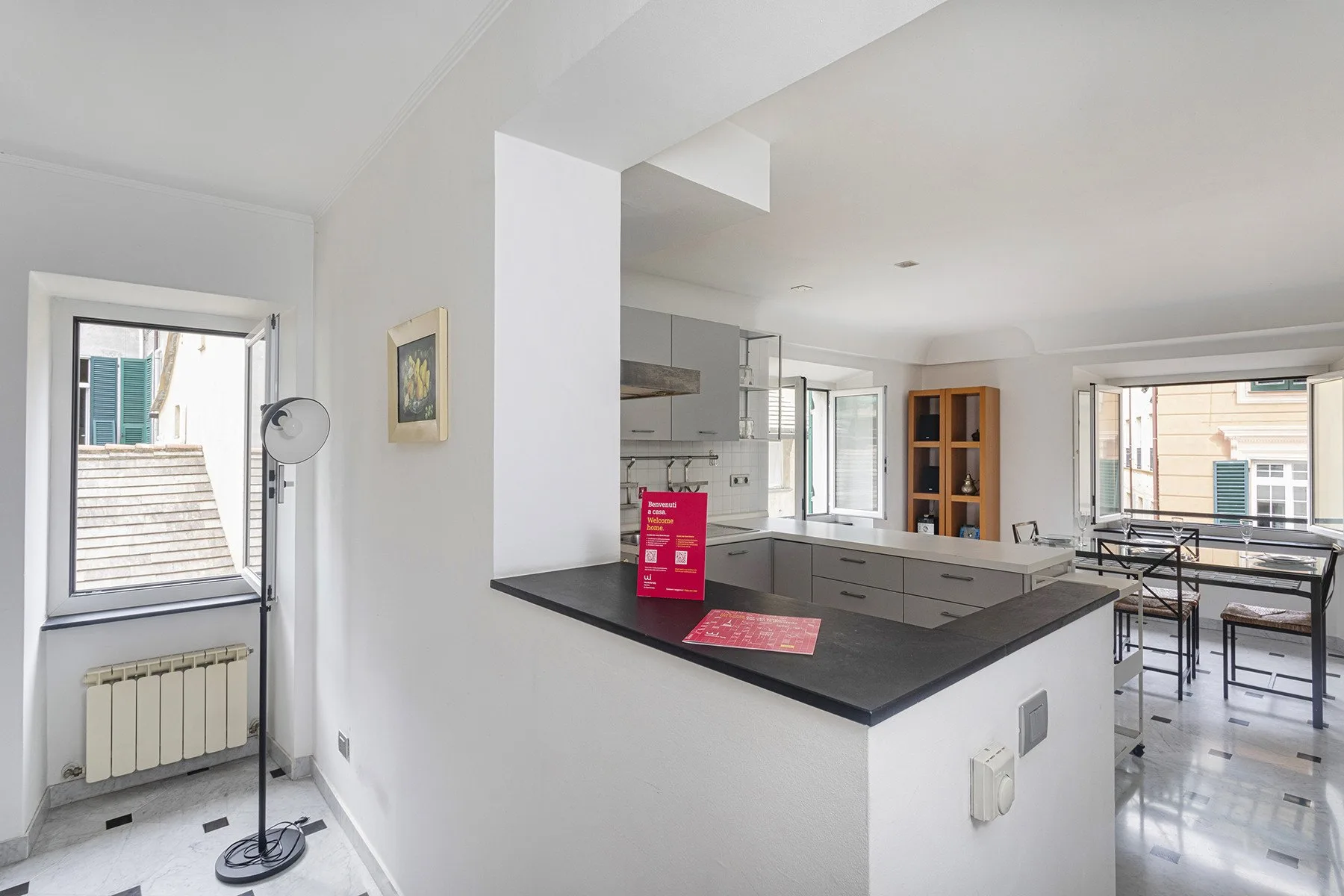 Una luminosa cocina abierta al comedor, con una encimera oscura y una mesa.