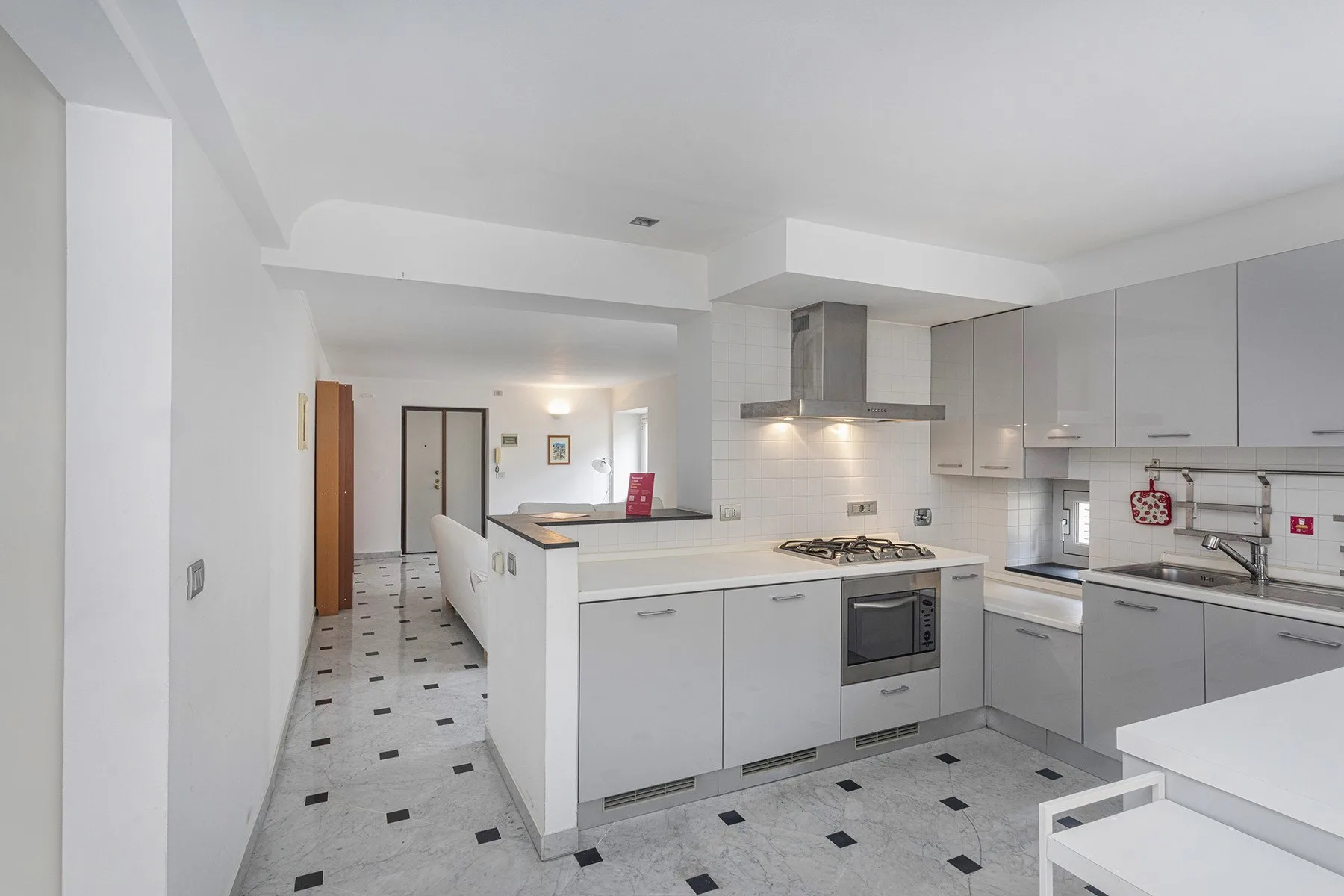 Una cocina luminosa con gabinetes blancos, una isla central y una placa de cocción.