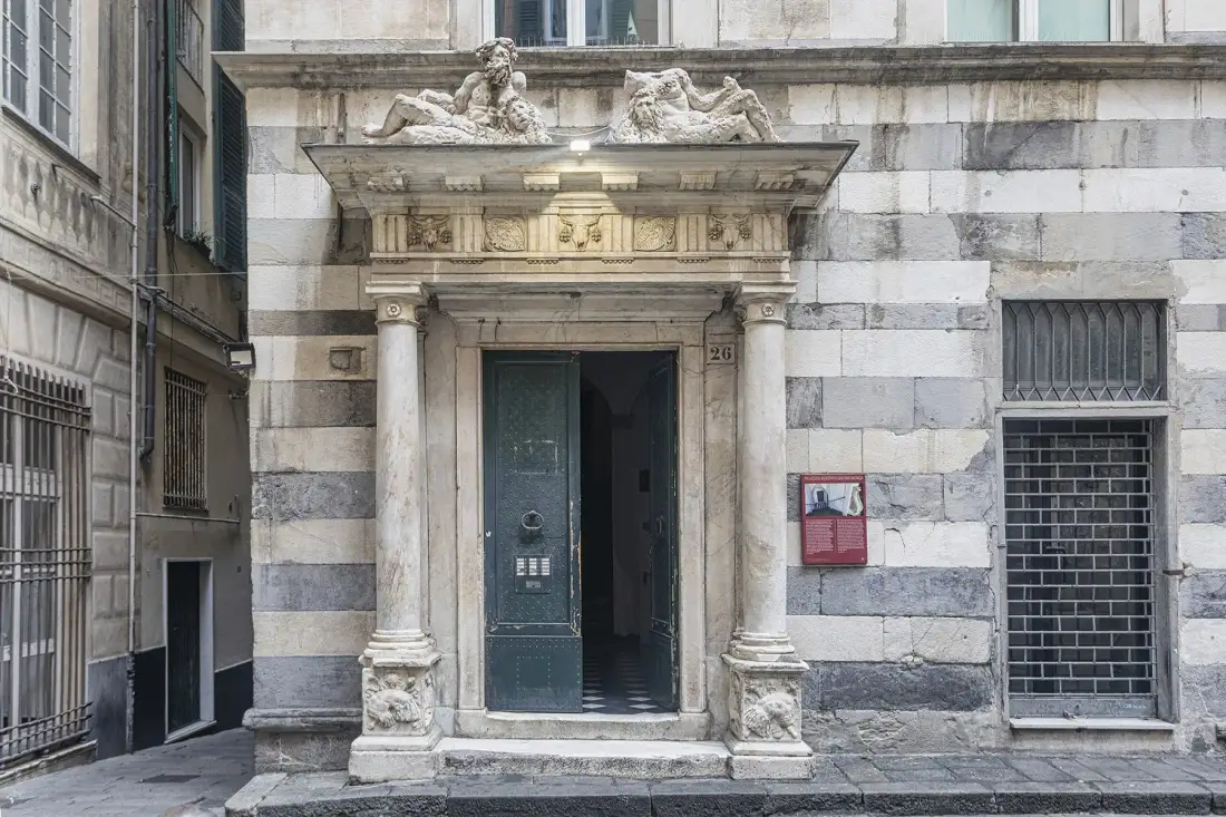 La entrada de un edificio de piedra tiene una puerta ornamentada junto a ventanas con rejas.
