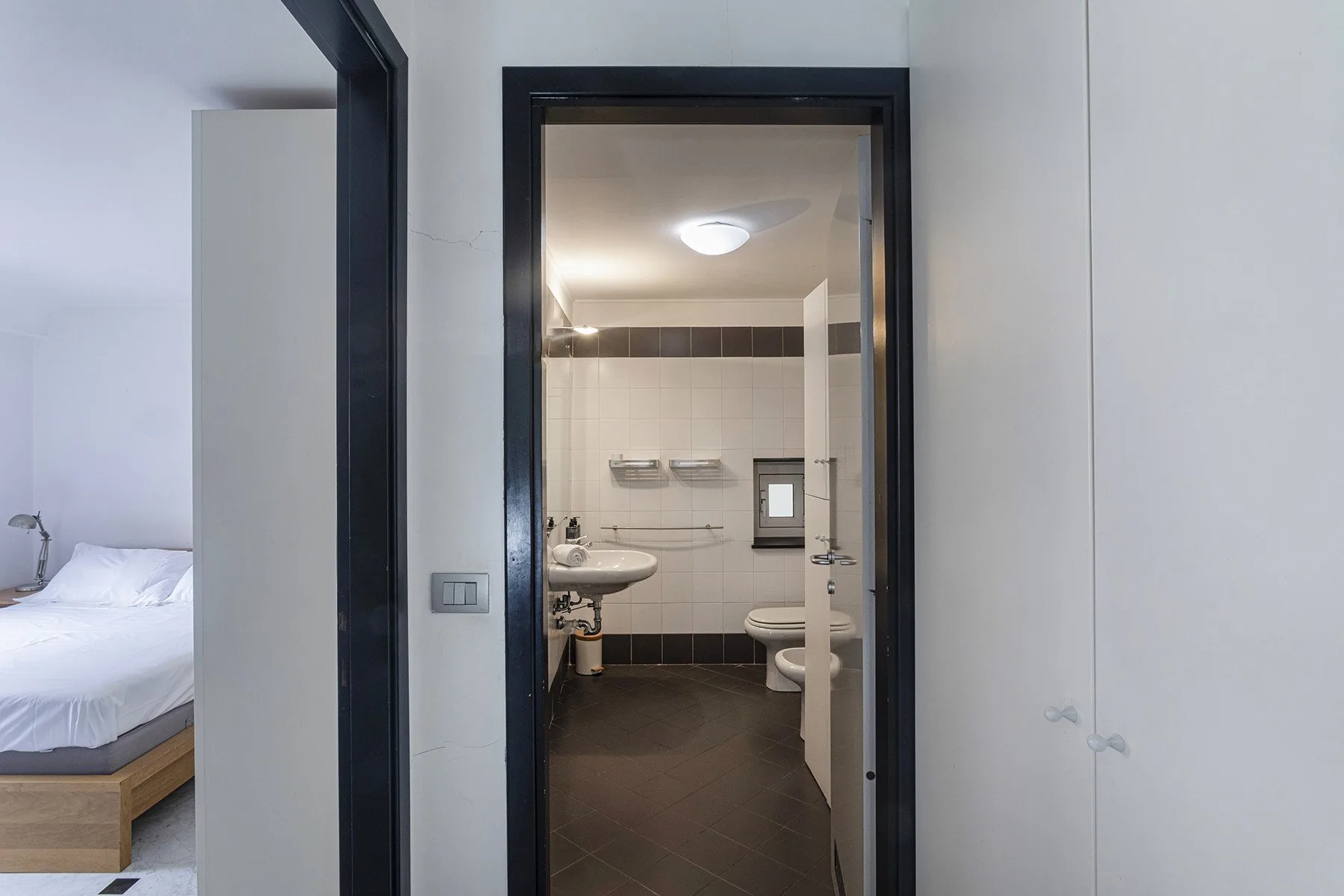 Un baño con inodoro y lavabo se ve a través de una puerta abierta.