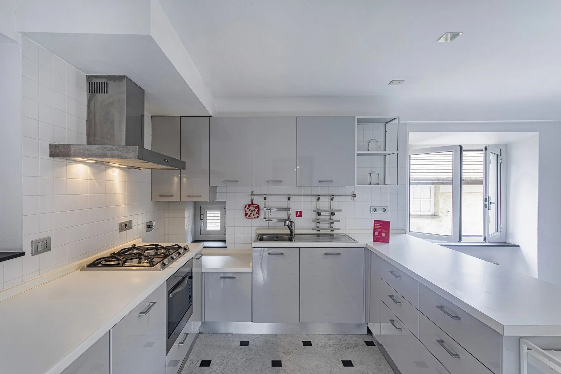 Una cocina moderna con gabinetes grises, encimeras blancas y una ventana.