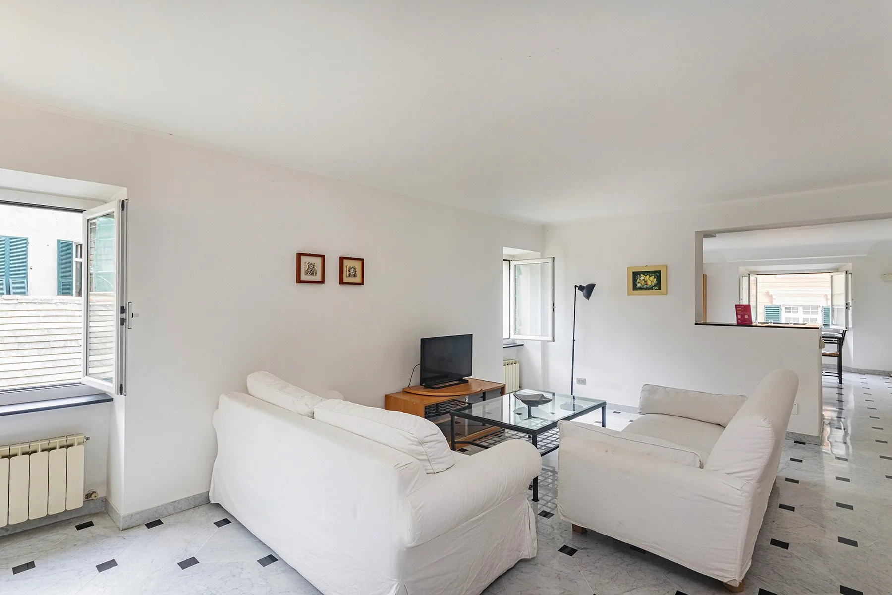 Una sala luminosa con asientos blancos y una mesa de centro de cristal.