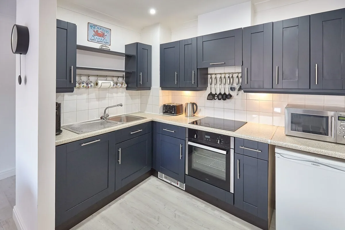 A modern kitchen with dark cabinets, a countertop, and built-in appliances.