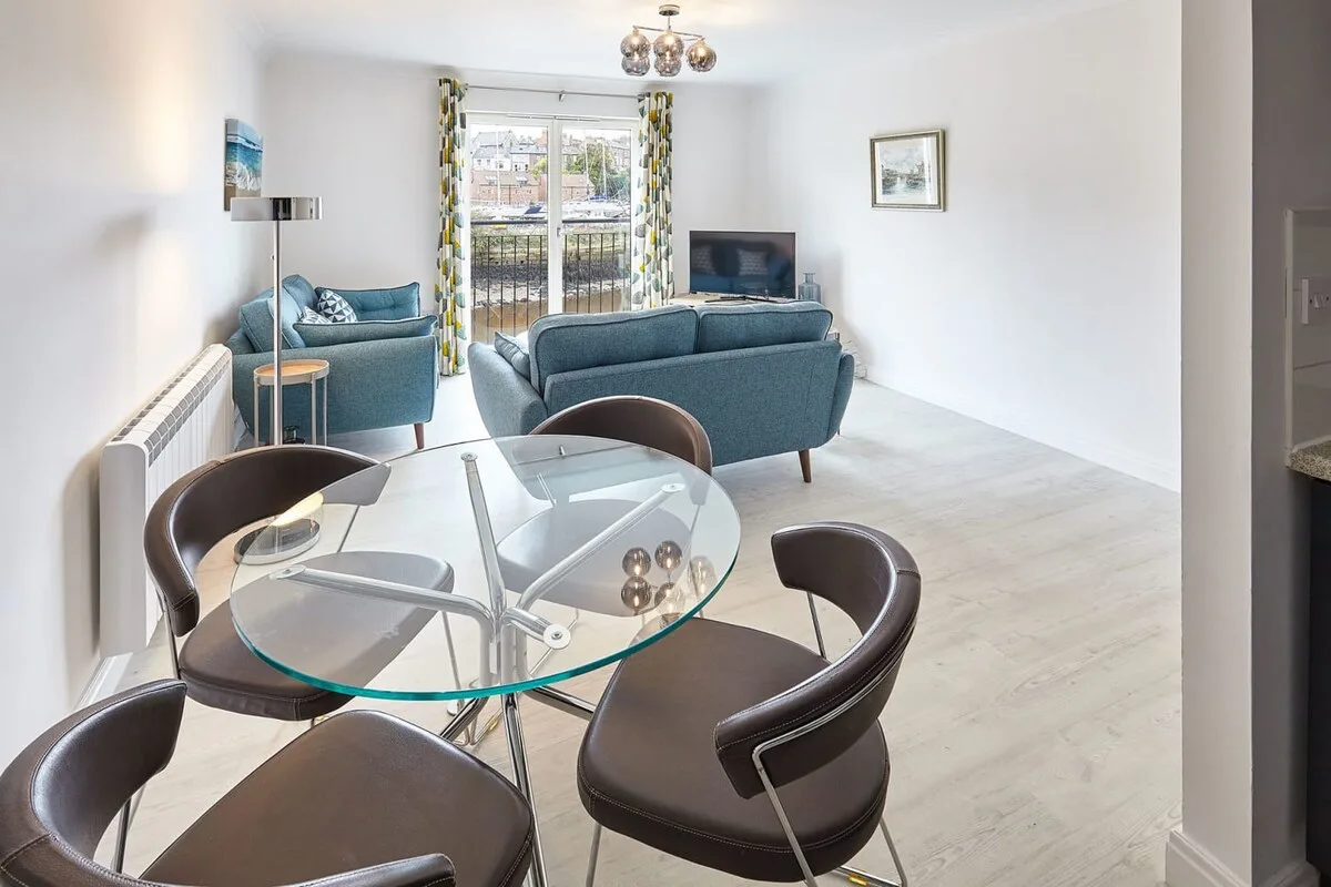 A bright living and dining area with seating around a glass table.