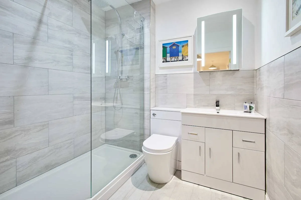 A bathroom with a glass shower, toilet, and vanity.
