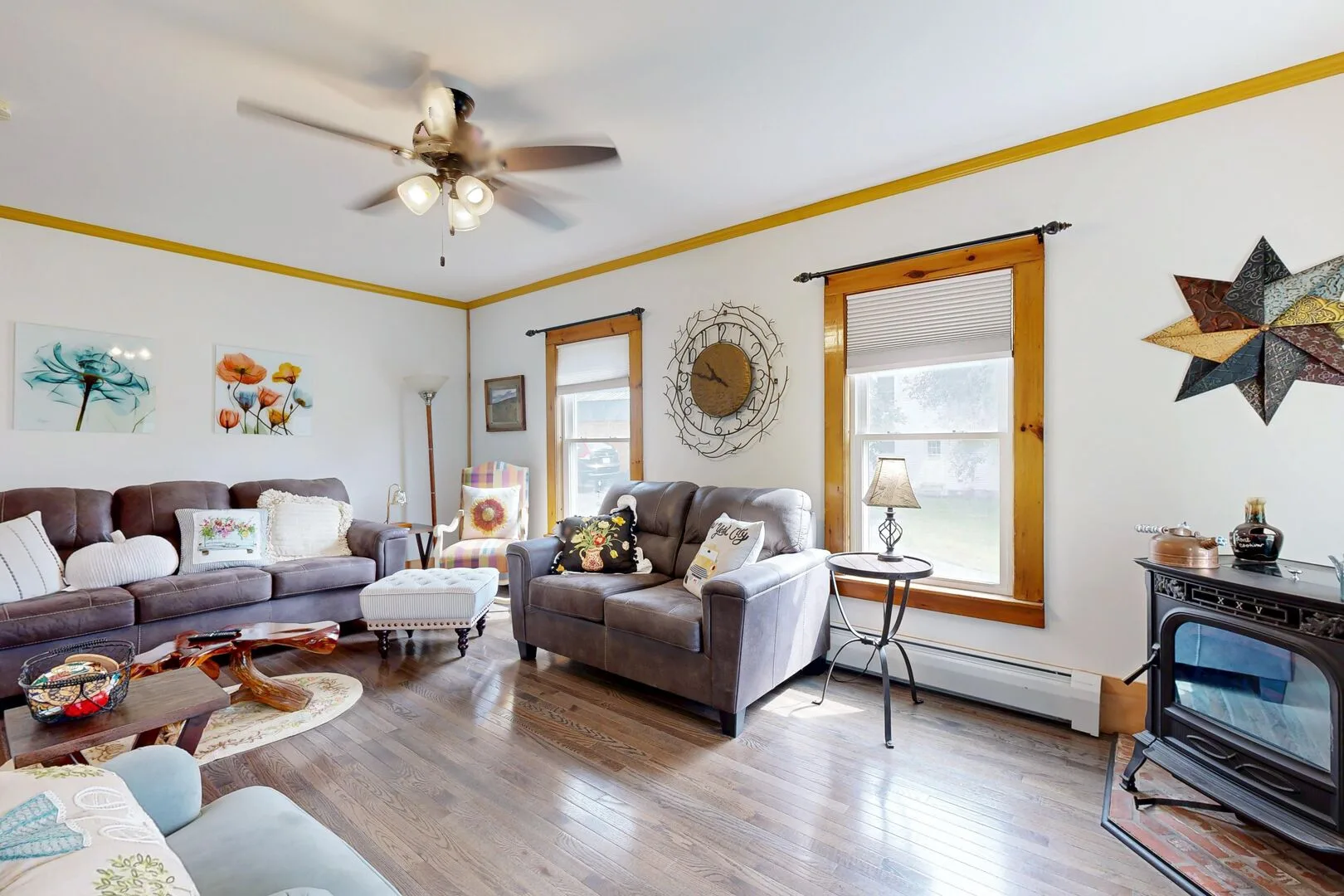 A living room with seating, framed artwork, and a ceiling fan.