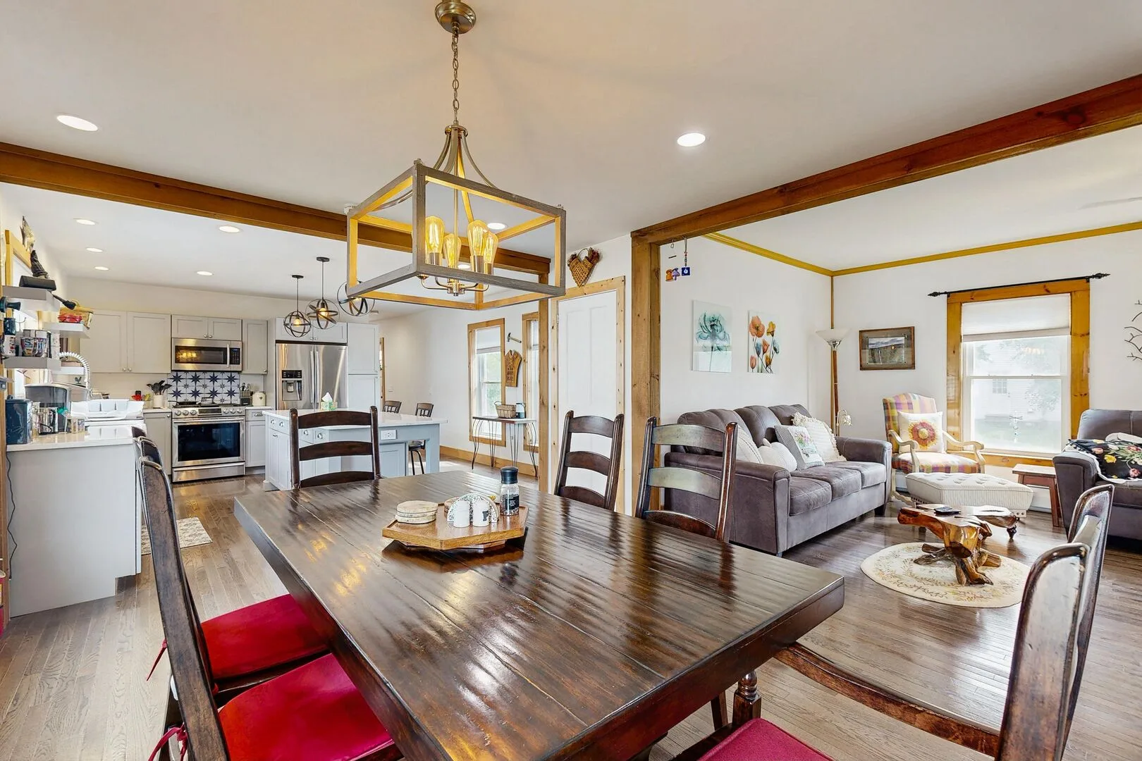 An open-plan dining and living area with a kitchen and dark wood dining table.