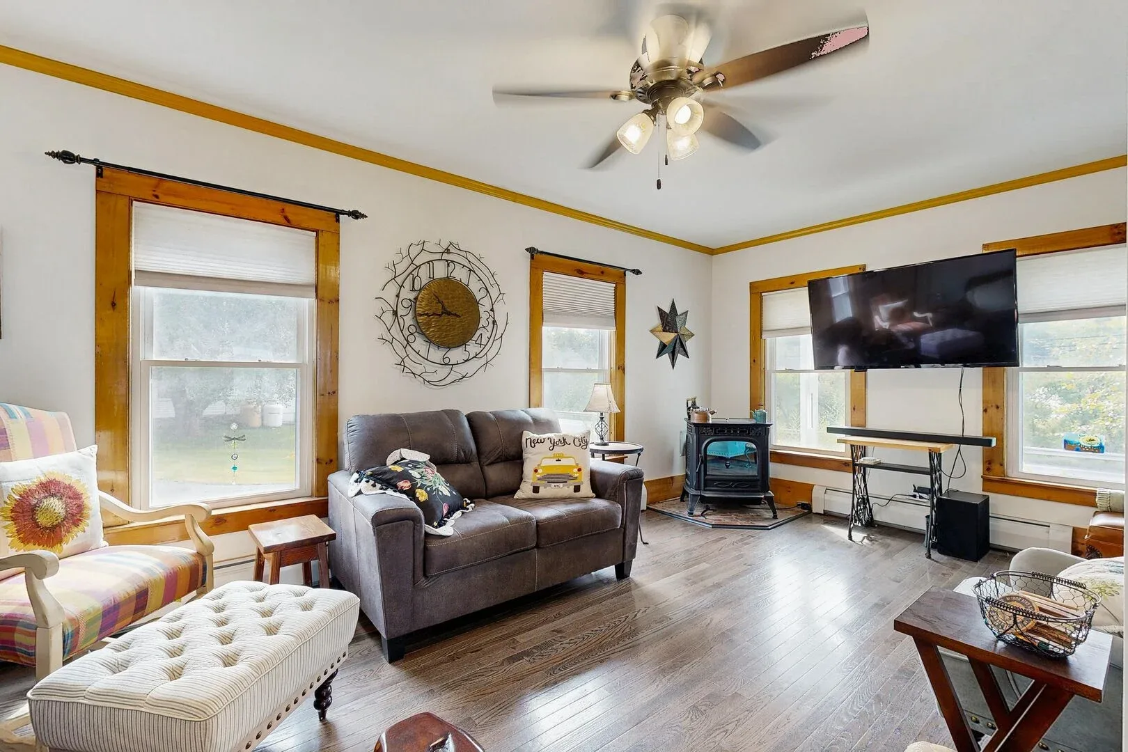 A bright living room with seating, large windows, and a television.