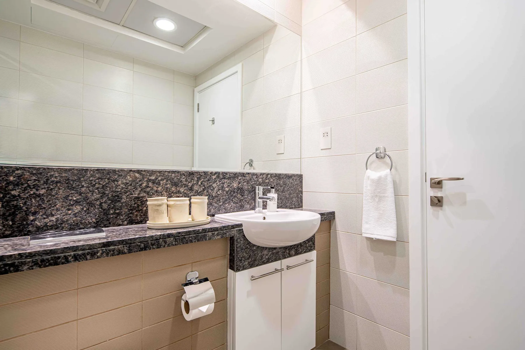 Un lavabo de baño con espejo y una toalla colgada en la pared.