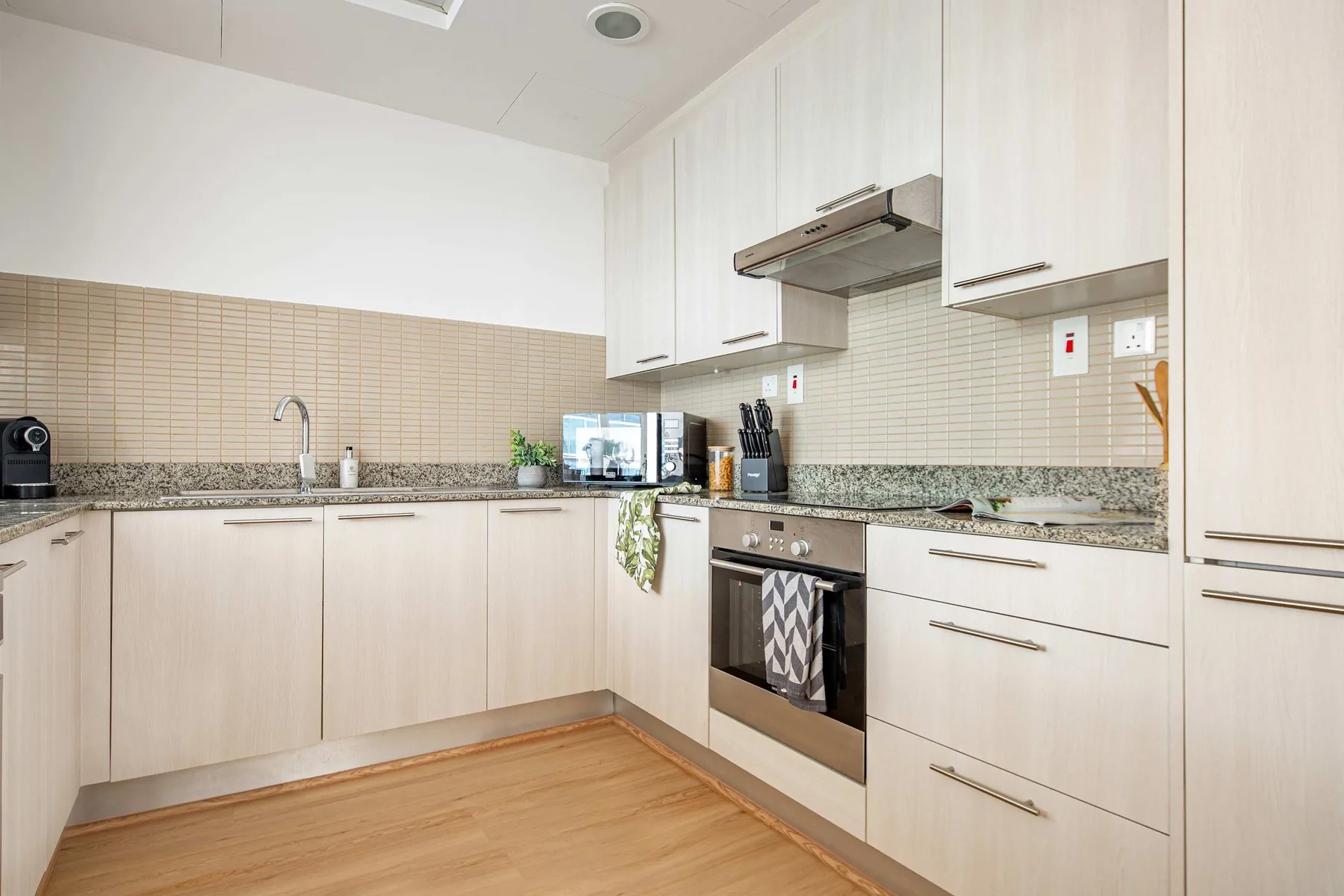 Una cocina luminosa con gabinetes claros, encimera y horno integrado.