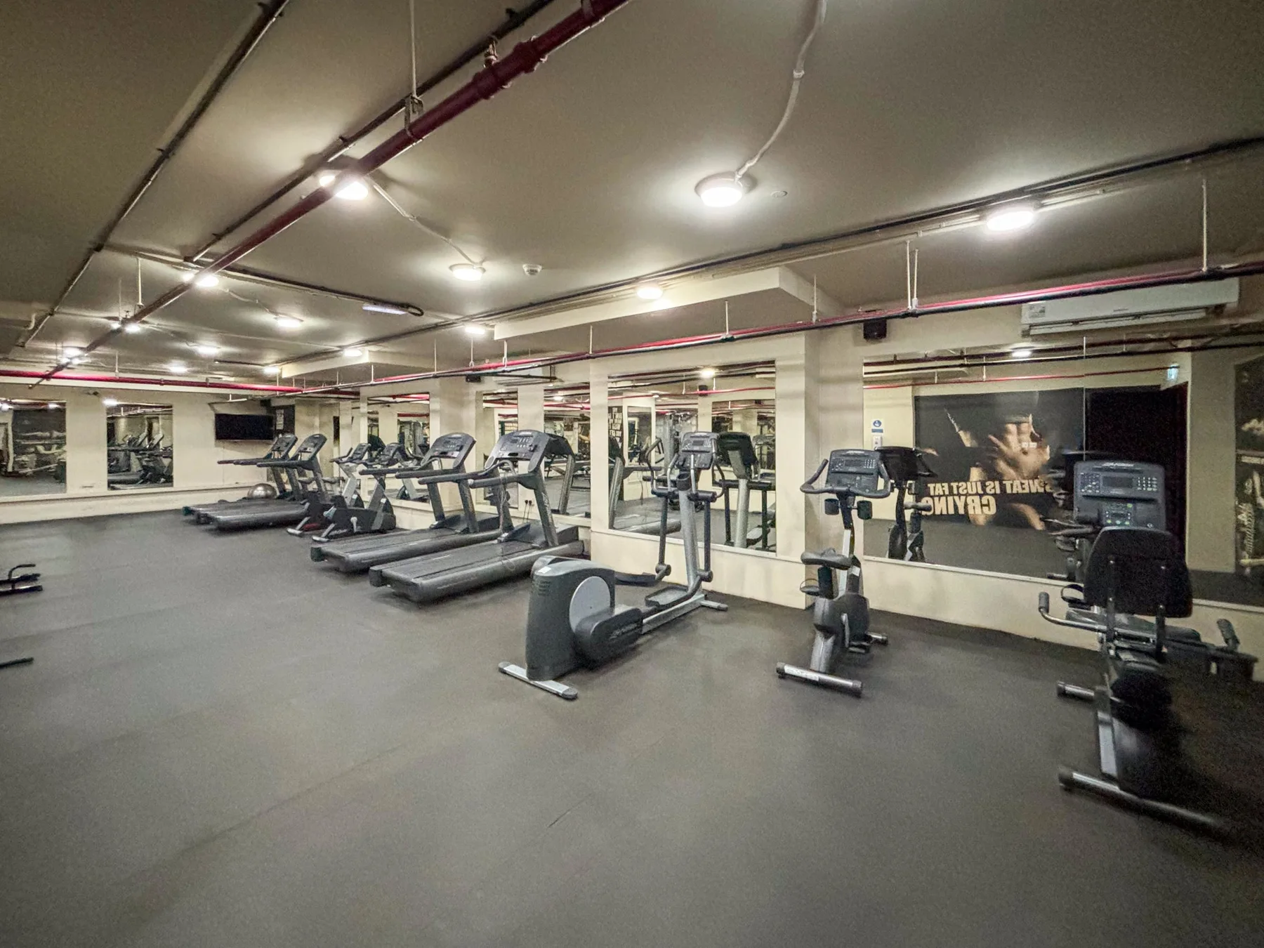 Un gimnasio amplio con cintas de correr y otros equipos de ejercicio.