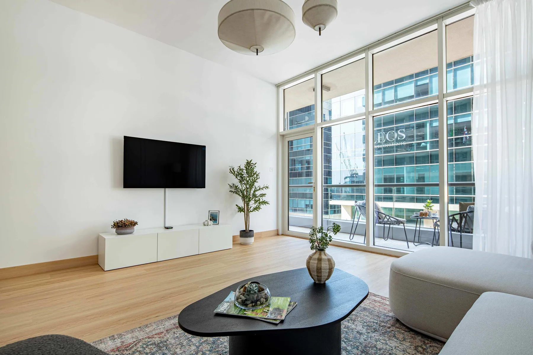 Una sala luminosa con ventanales de piso a techo y una zona de estar.