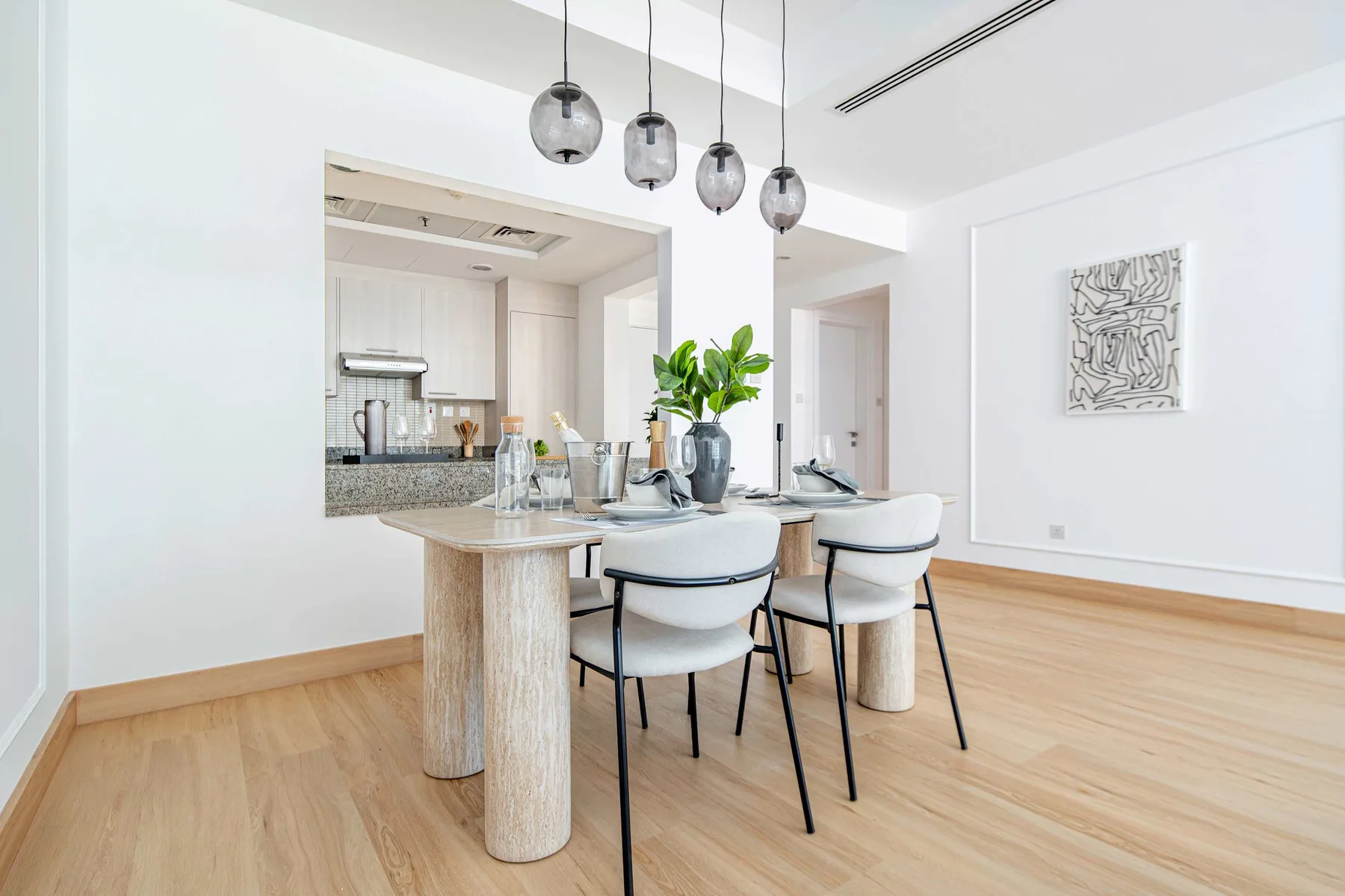Un comedor luminoso con la mesa puesta junto a una cocina abierta.