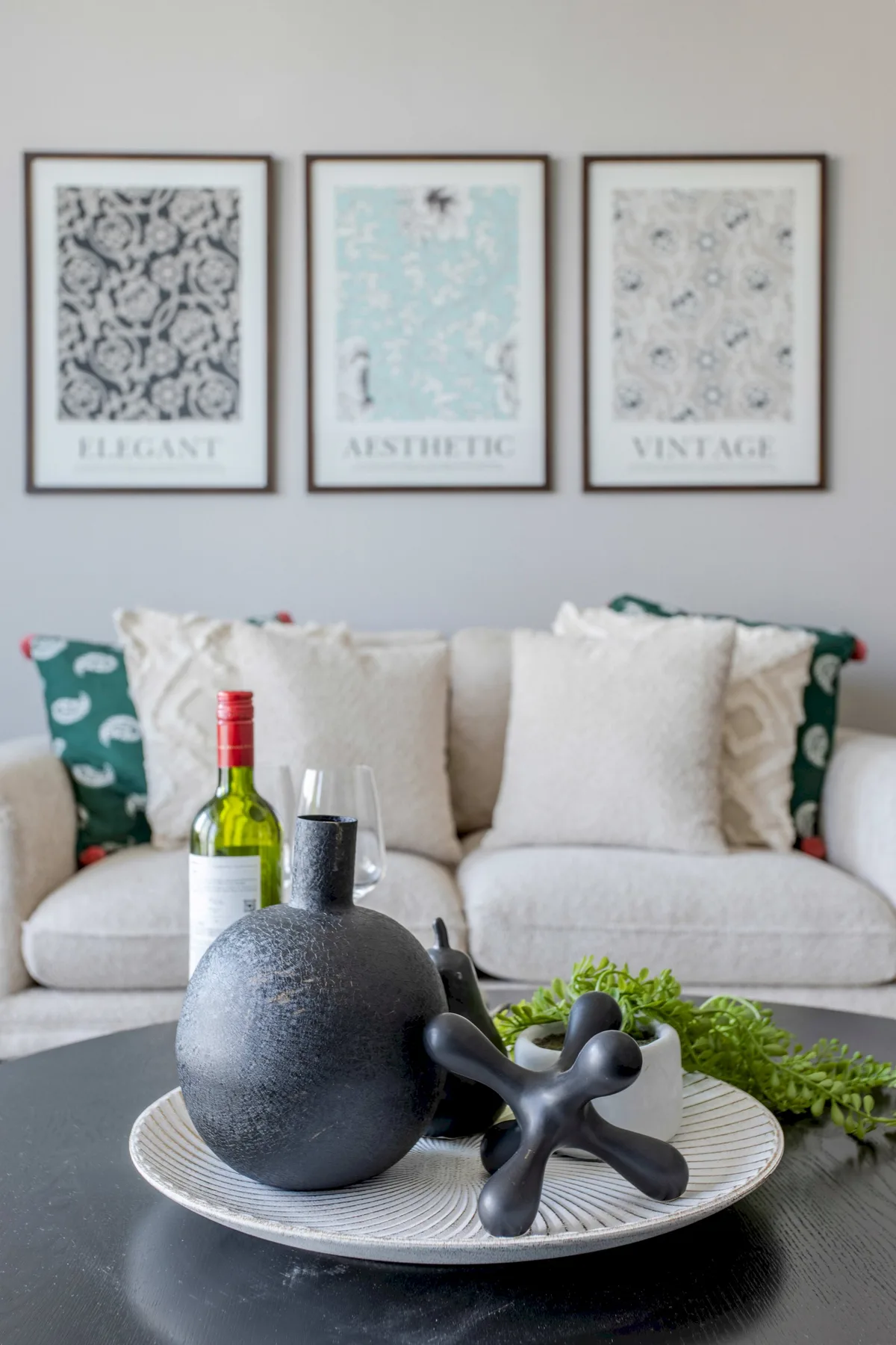 Una zona de estar con cuadros sobre un sofá y objetos decorativos en una mesa.