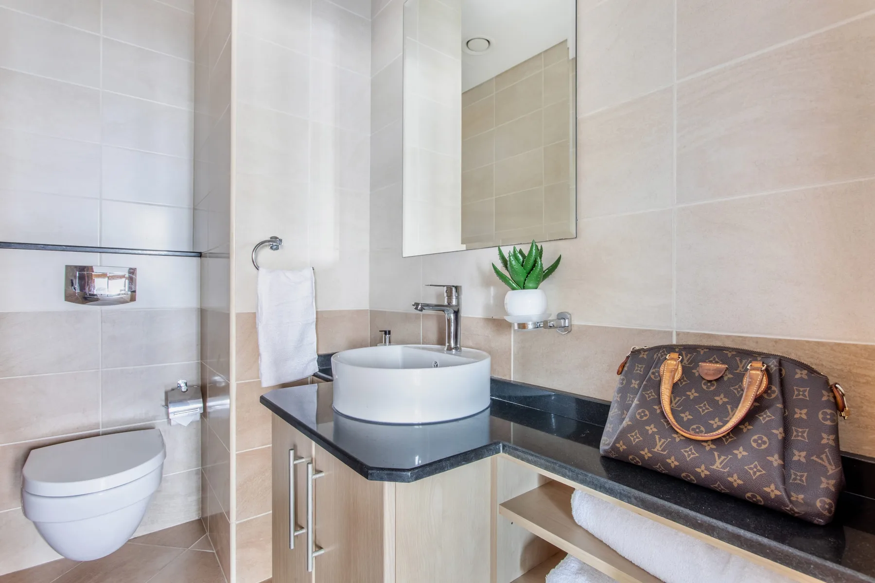 Un lavabo de baño con azulejos, espejo de pared y toalla.