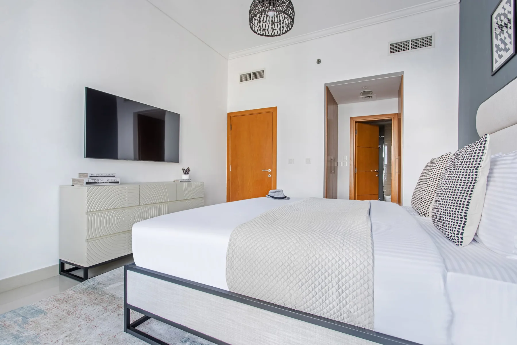 Un dormitorio con una cama bien arreglada, un televisor y una cómoda.