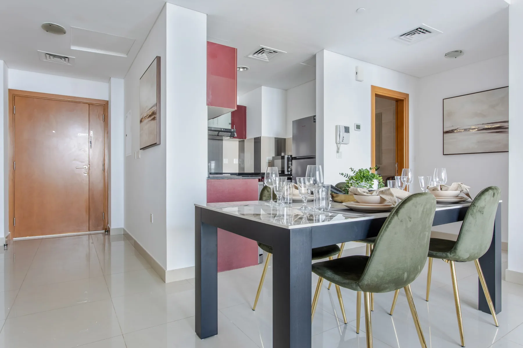 Comedor con la mesa puesta junto a una cocina y un pasillo.