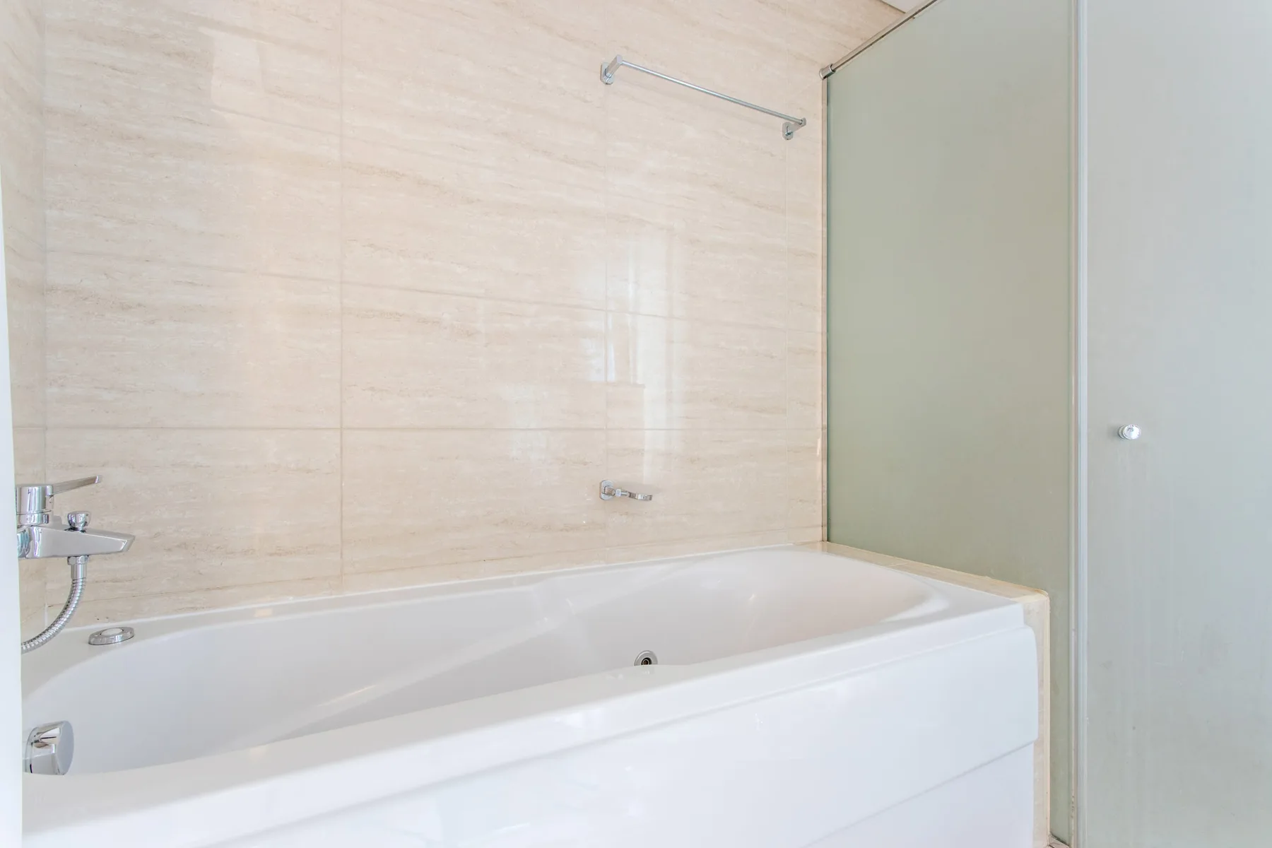 Un baño con una bañera y paredes revestidas de azulejos.