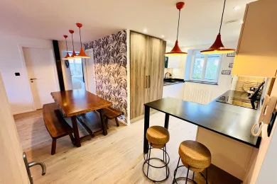 An open-plan kitchen and dining area with a wooden table and breakfast counter.