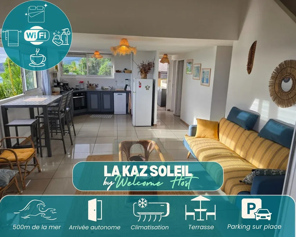 A bright open-plan living area combines a yellow sofa, dining table, and compact kitchen.