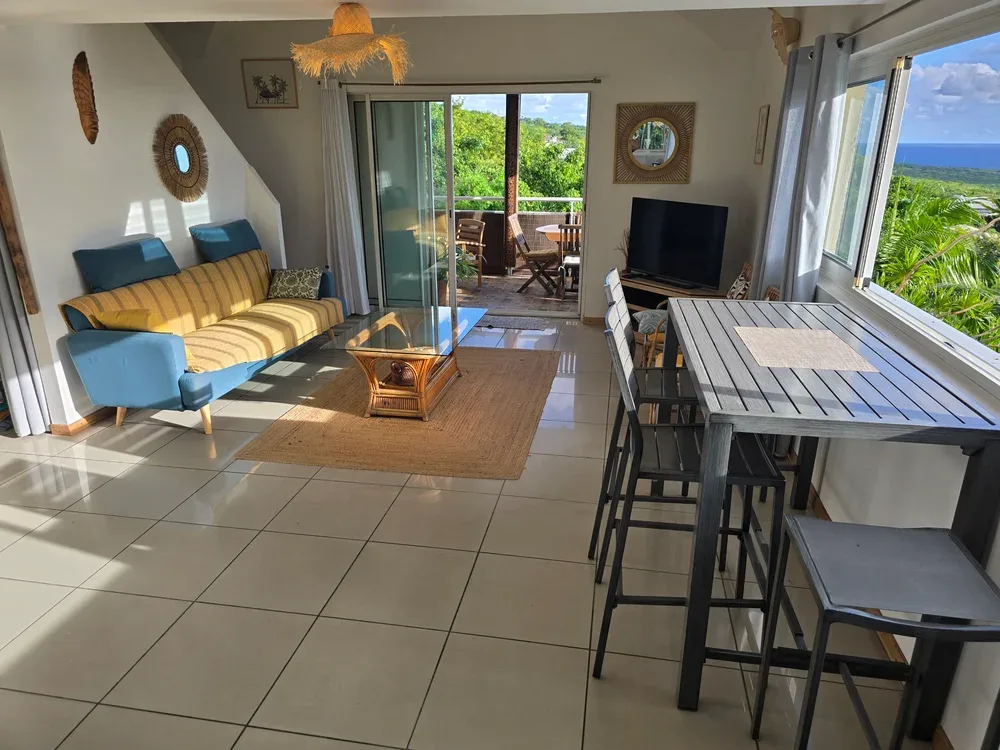 A bright living and dining area opens through sliding doors to a leafy outdoor patio.
