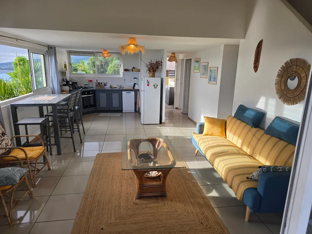 A combined living and kitchen area with a dining table and yellow sofa.