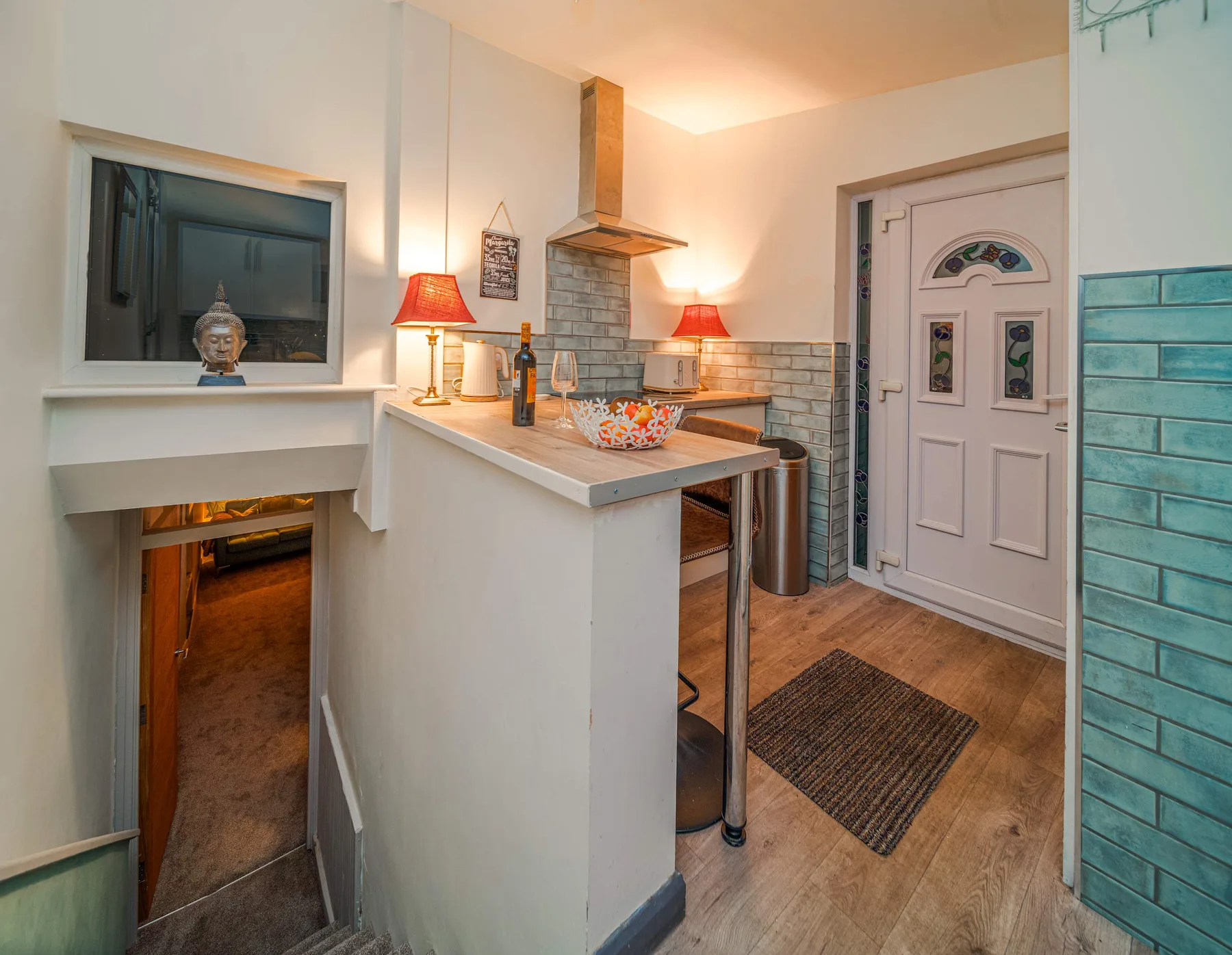 A kitchen with a peninsula counter, range hood, and entry door.