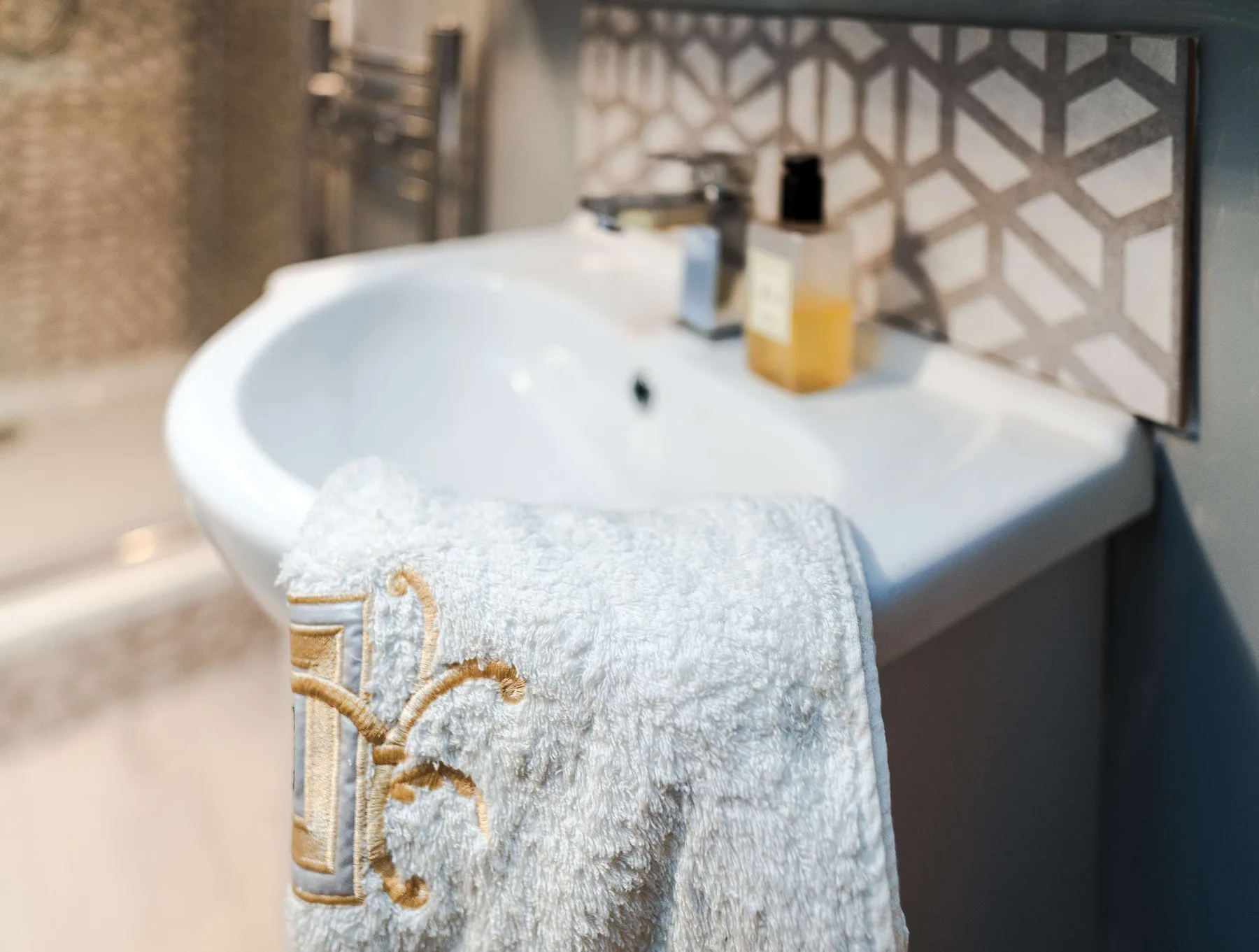 A bathroom sink with toiletries and a towel draped over its edge.