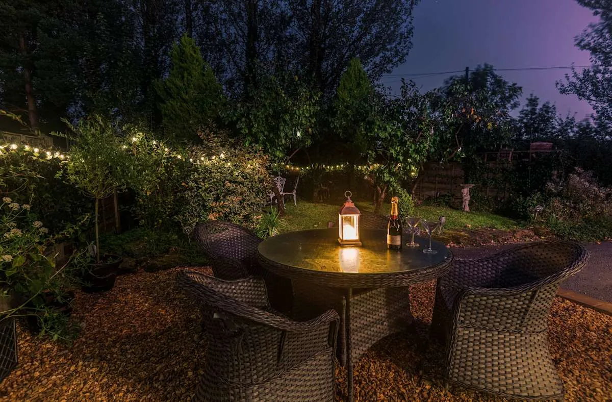An outdoor dining area with a lantern on the table at dusk.