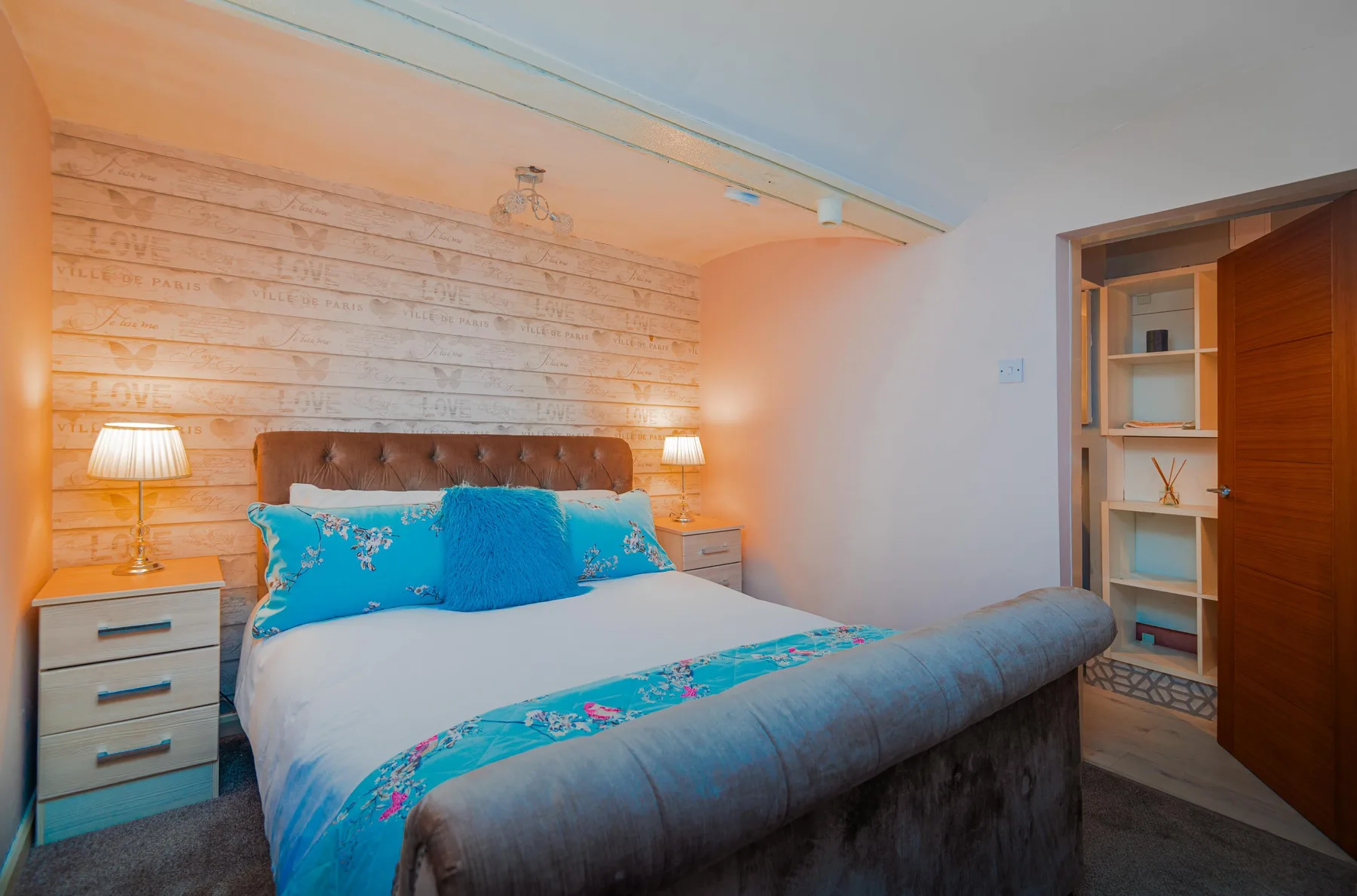 A bedroom with a bed dressed in blue and turquoise bedding.