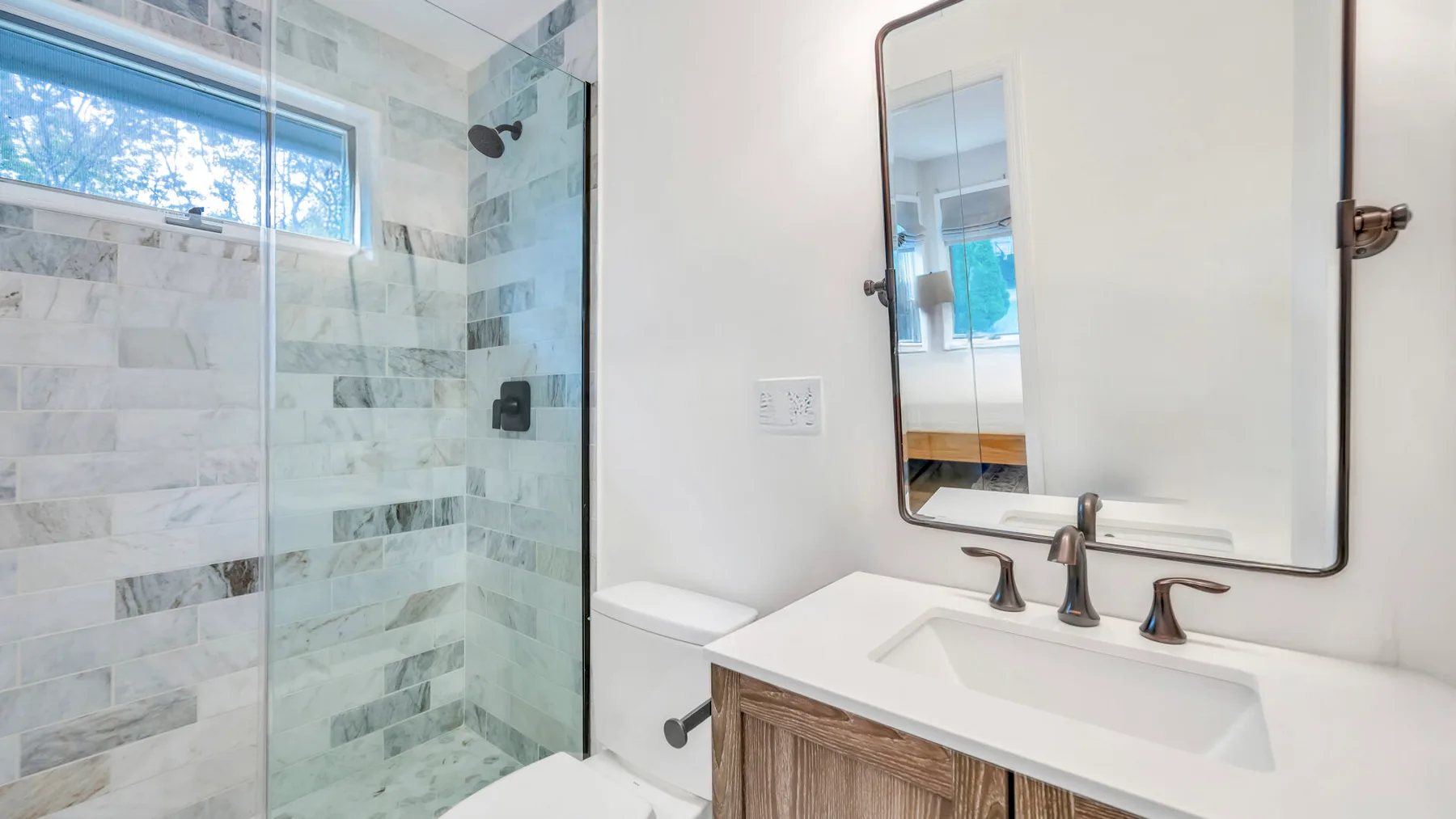 Un baño con una ducha de vidrio y un lavabo bajo un espejo.