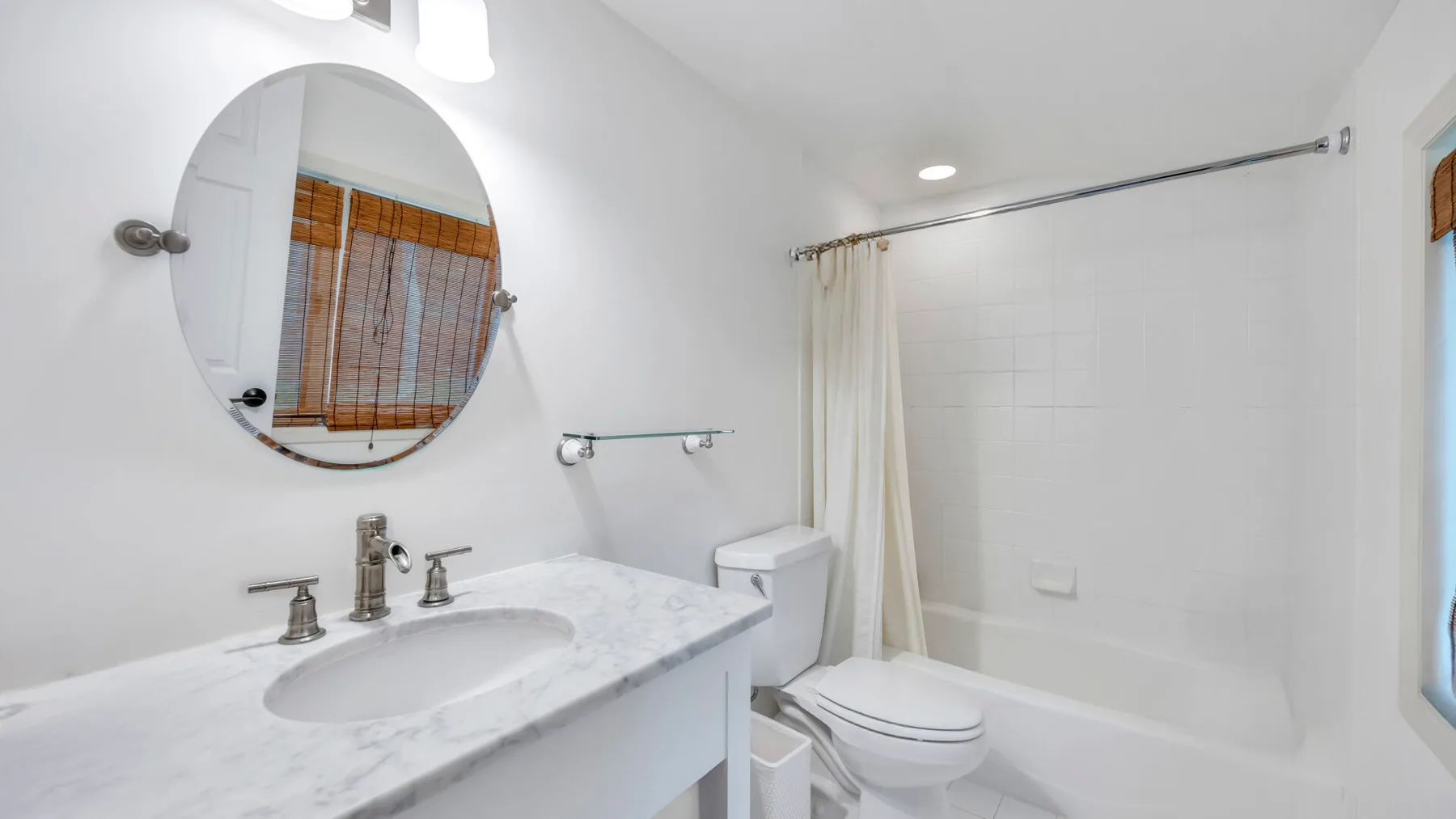 Un baño luminoso con lavabo, inodoro y bañera detrás de una cortina de ducha.