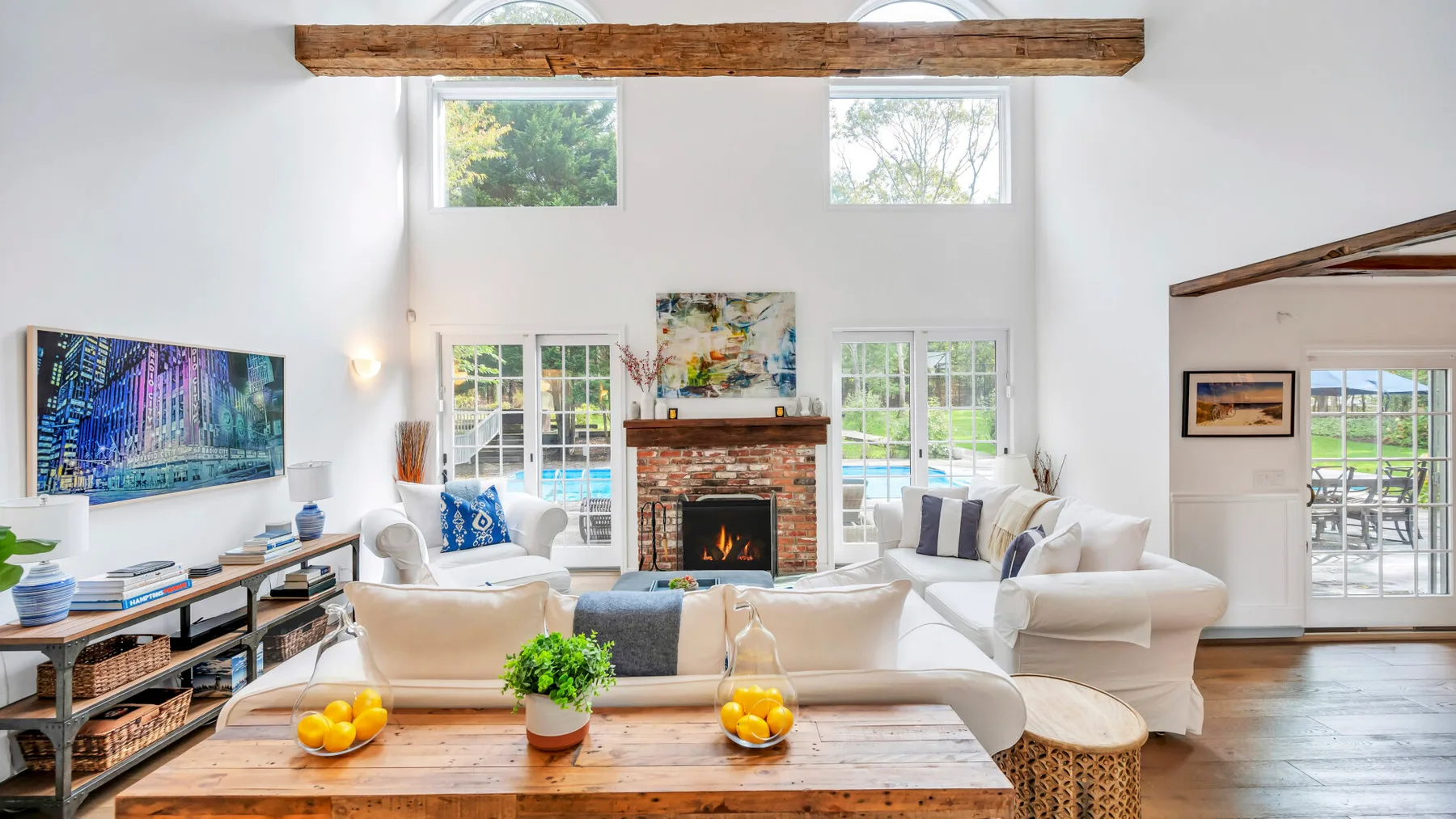 A bright living room with seating arranged around a brick fireplace and coffee table.