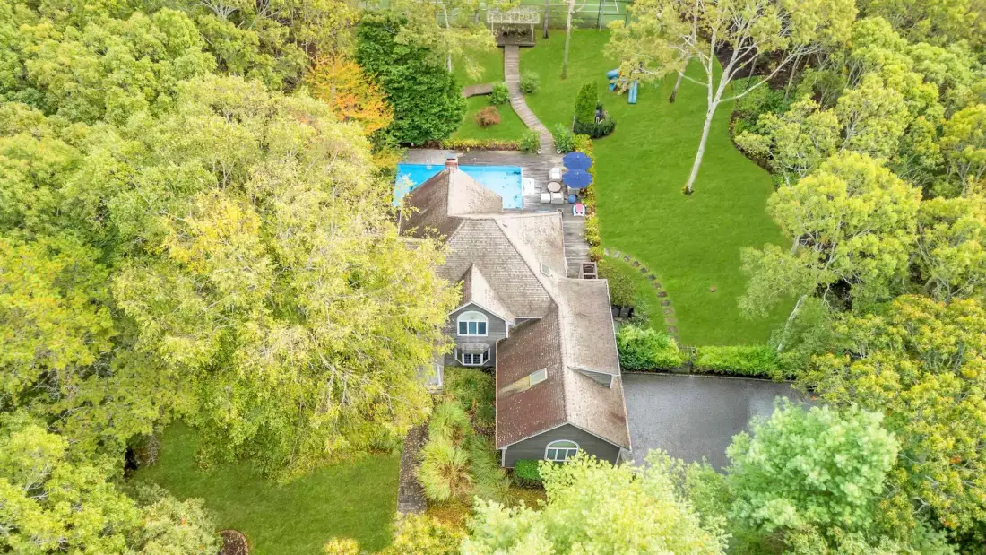 Vista aérea de una casa junto a una piscina y jardines.