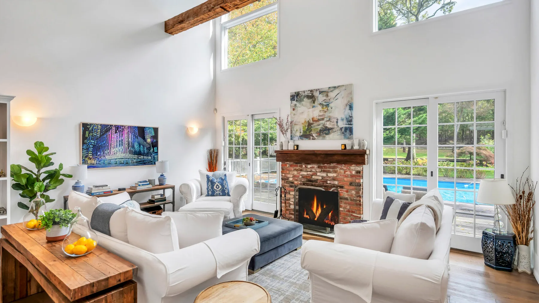 A bright living room with seating arranged around a brick fireplace and glass doors.
