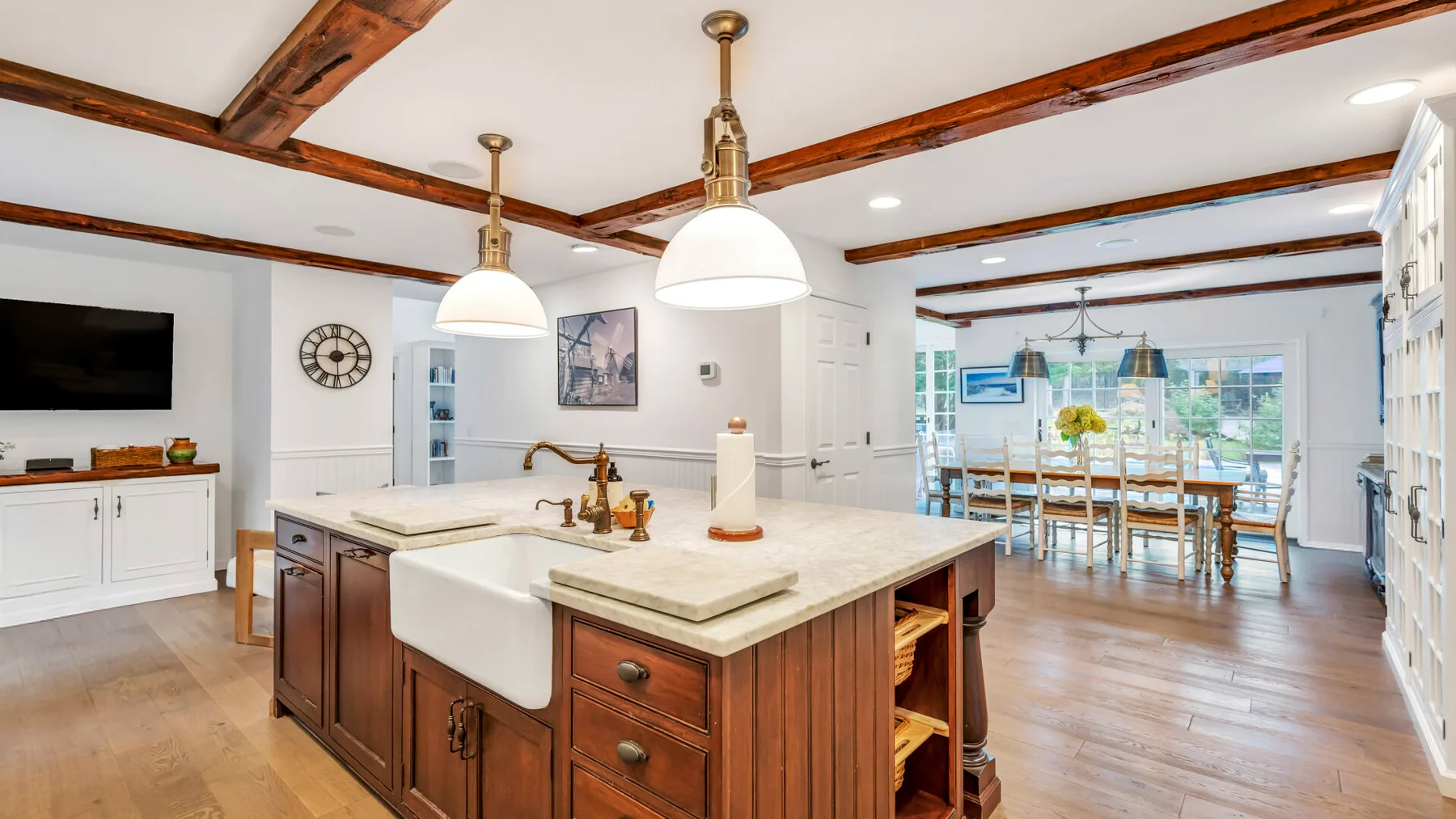 Una luminosa cocina abierta con comedor incluye una isla central y una mesa junto a las ventanas.