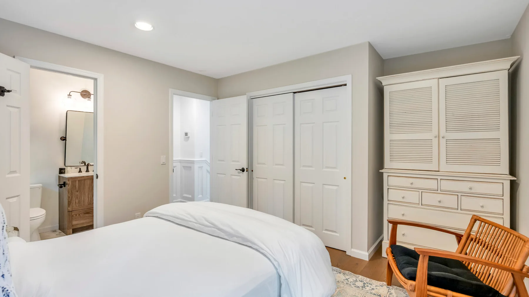 Un dormitorio con una cama, un armario y una puerta abierta al baño.