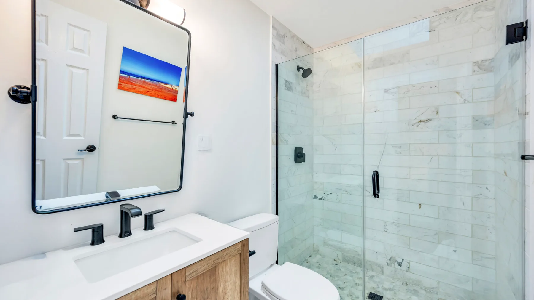 Un baño con lavabo, espejo y ducha de vidrio.