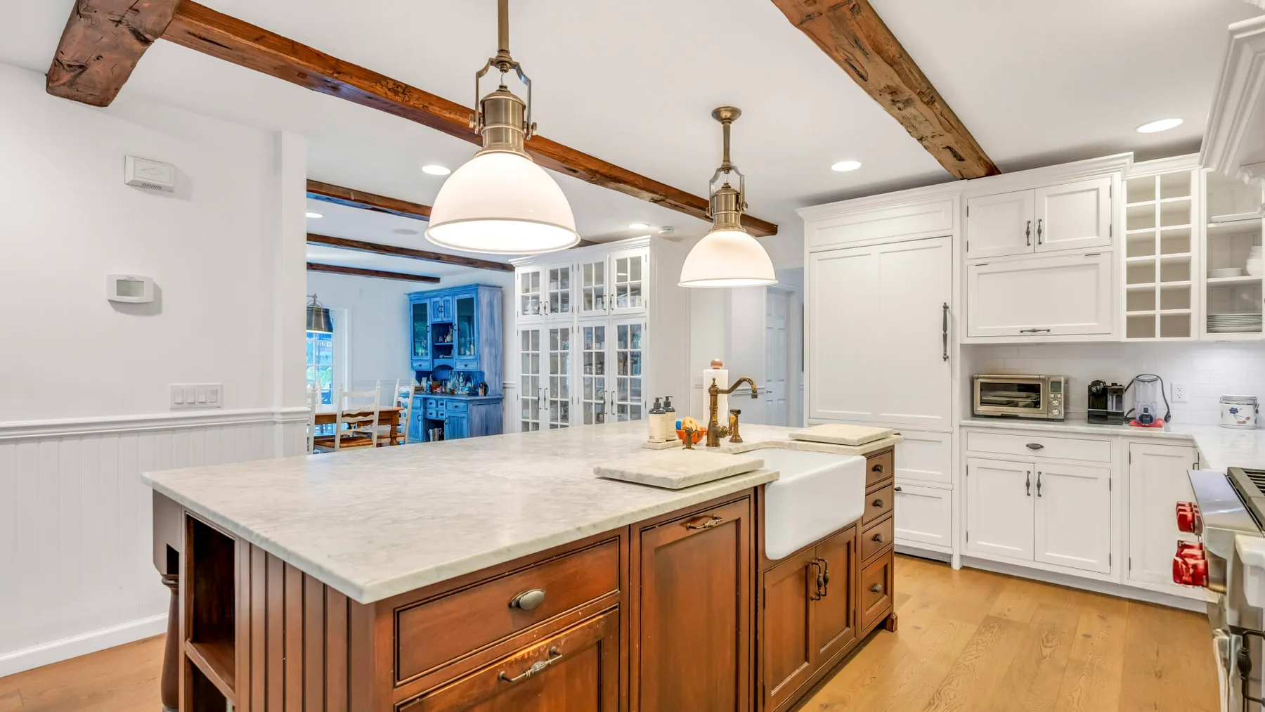 Una cocina luminosa con una isla grande y gabinetes blancos.